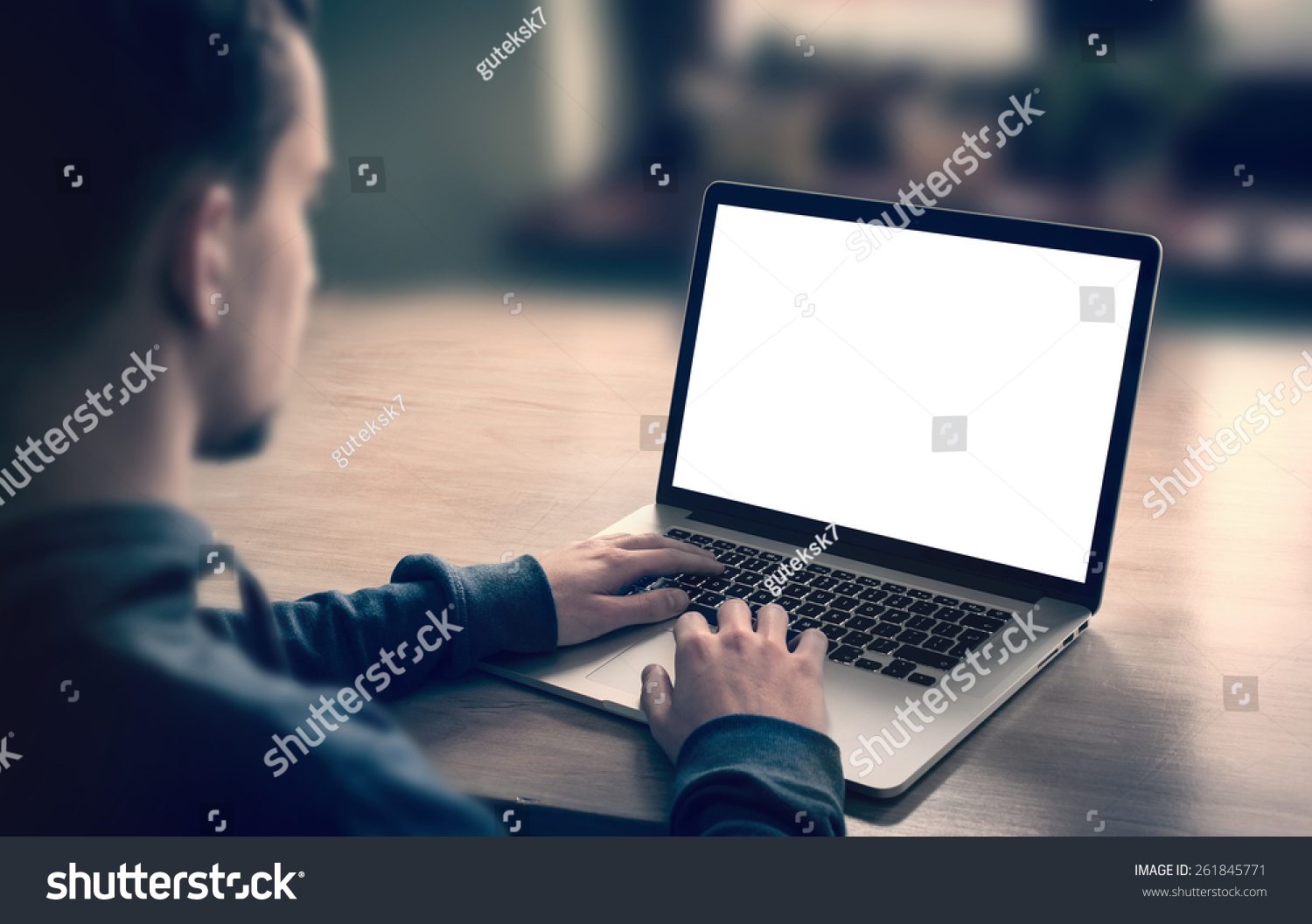 Man using  working on laptop with blank screen in home living room.