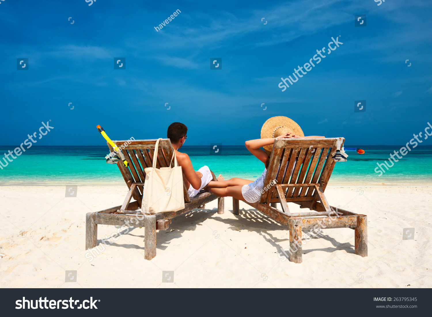 Couple in white relax on a tropical beach at Maldives