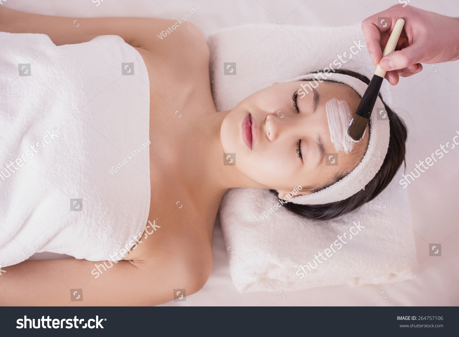Spa therapy for young asian woman receiving facial mask at beauty salon.