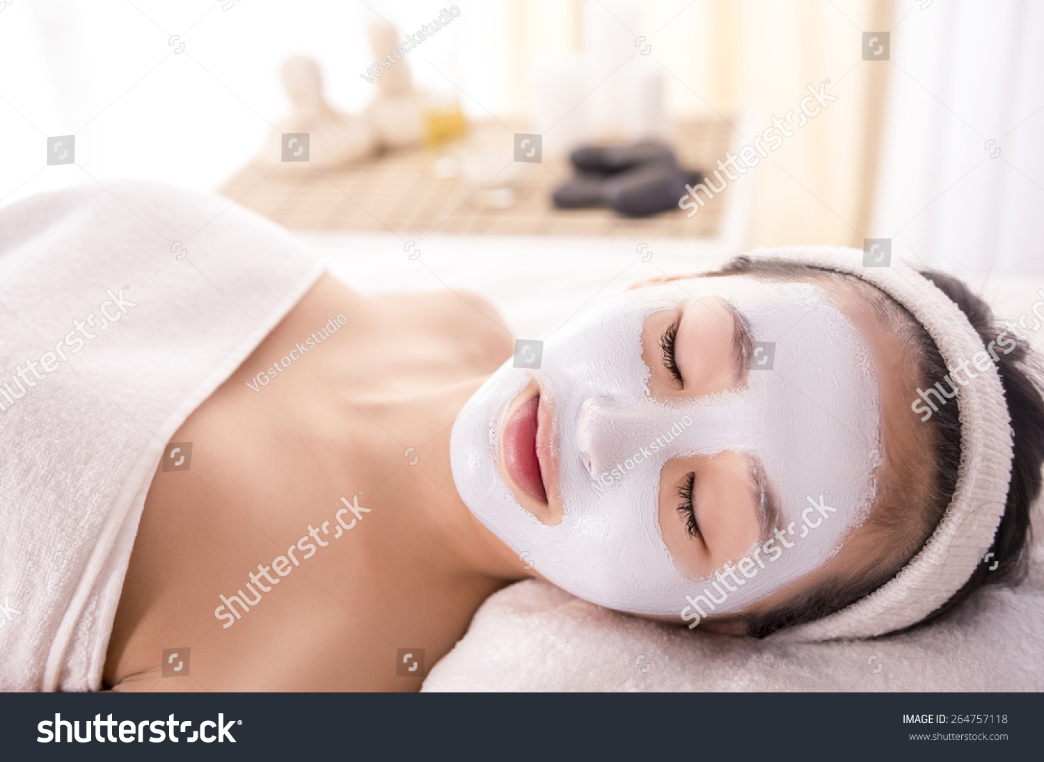 Spa therapy for young asian woman receiving facial mask at beauty salon.
