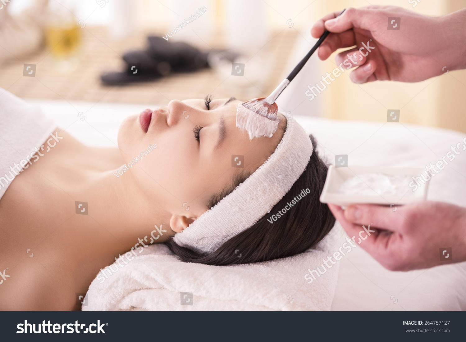 Spa therapy for young asian woman receiving facial mask at beauty salon.