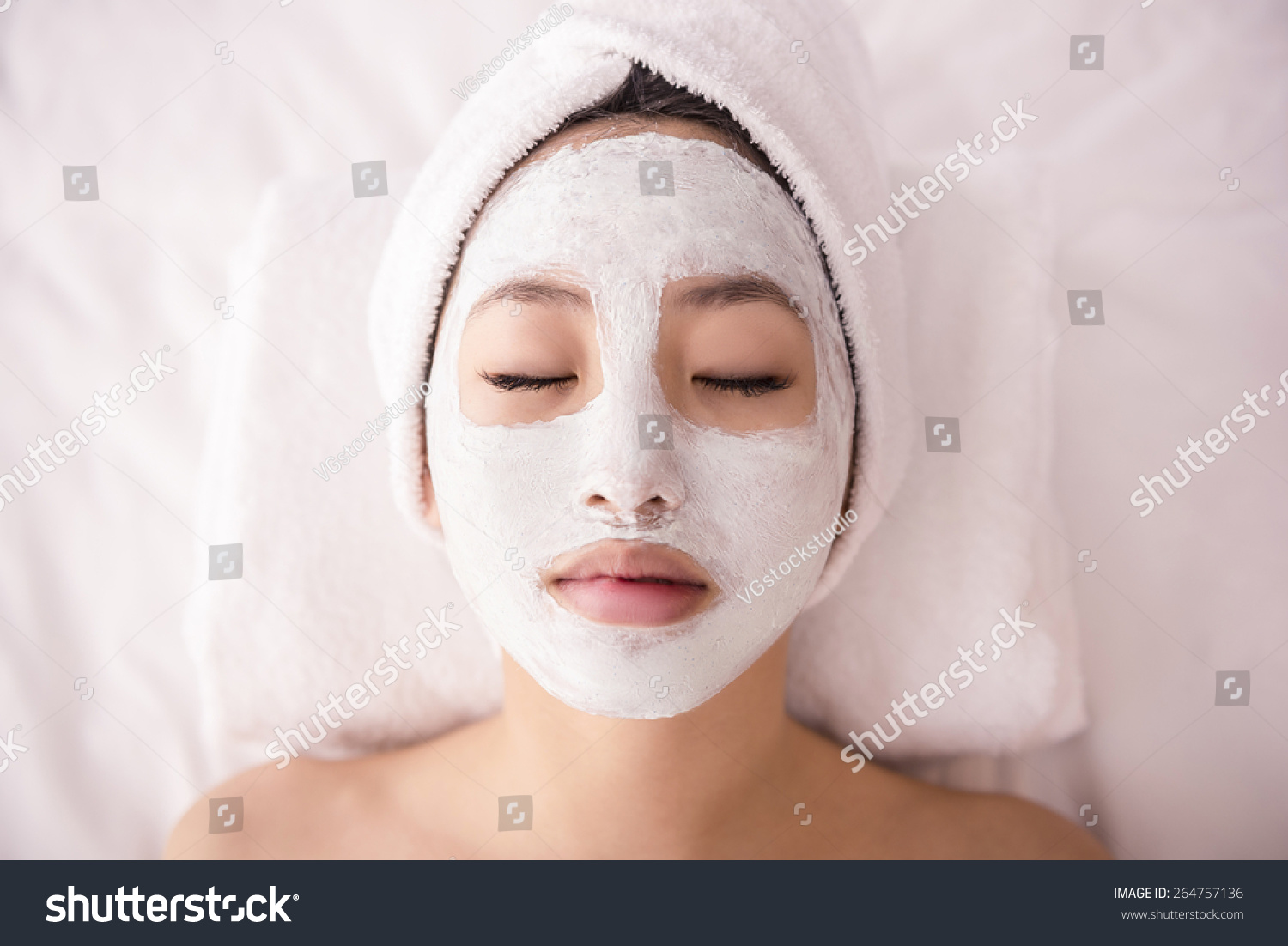 Spa therapy for young asian woman receiving facial mask at beauty salon.