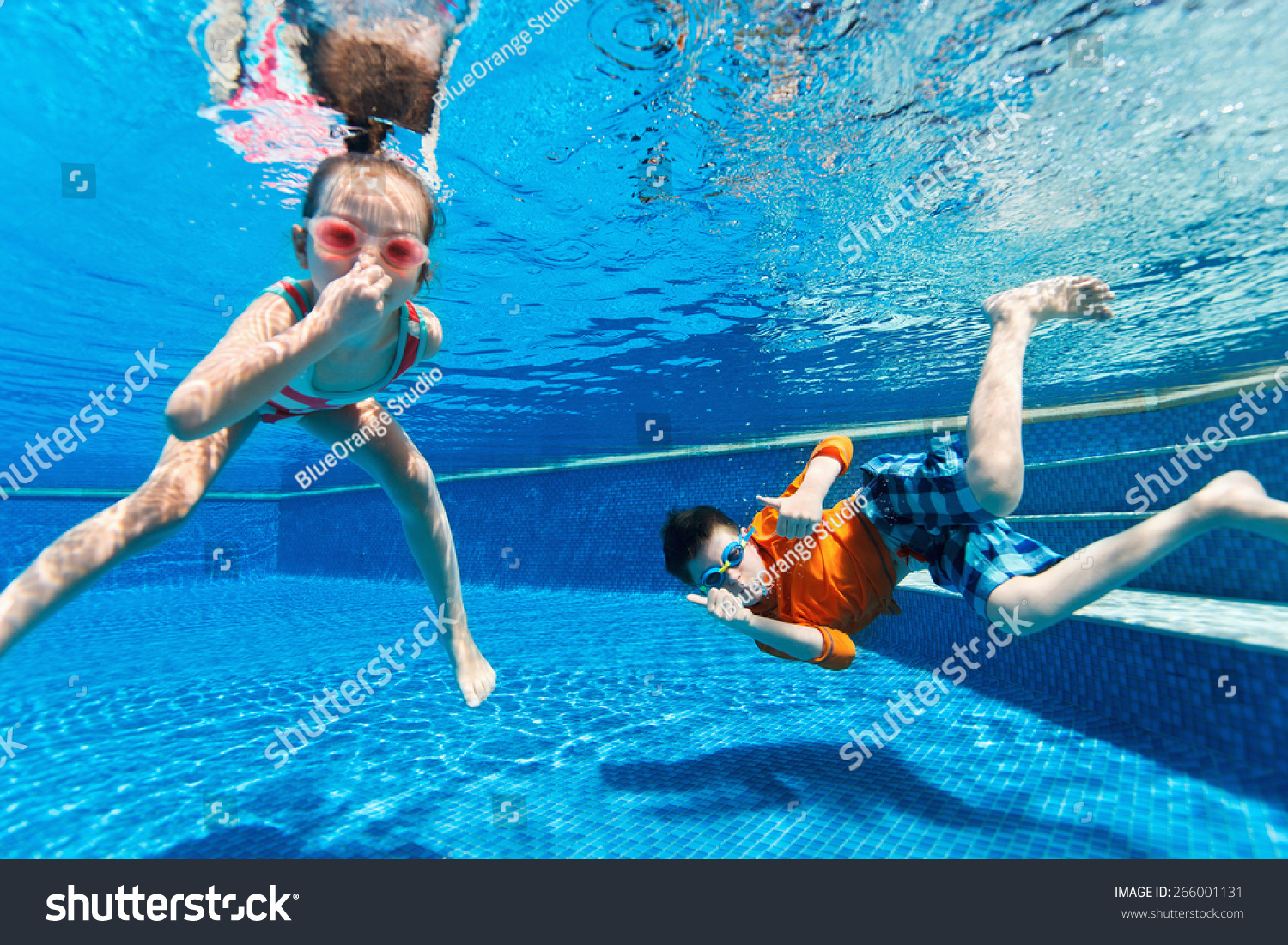 Kids having fun playing underwater in swimming pool on summer vacation
