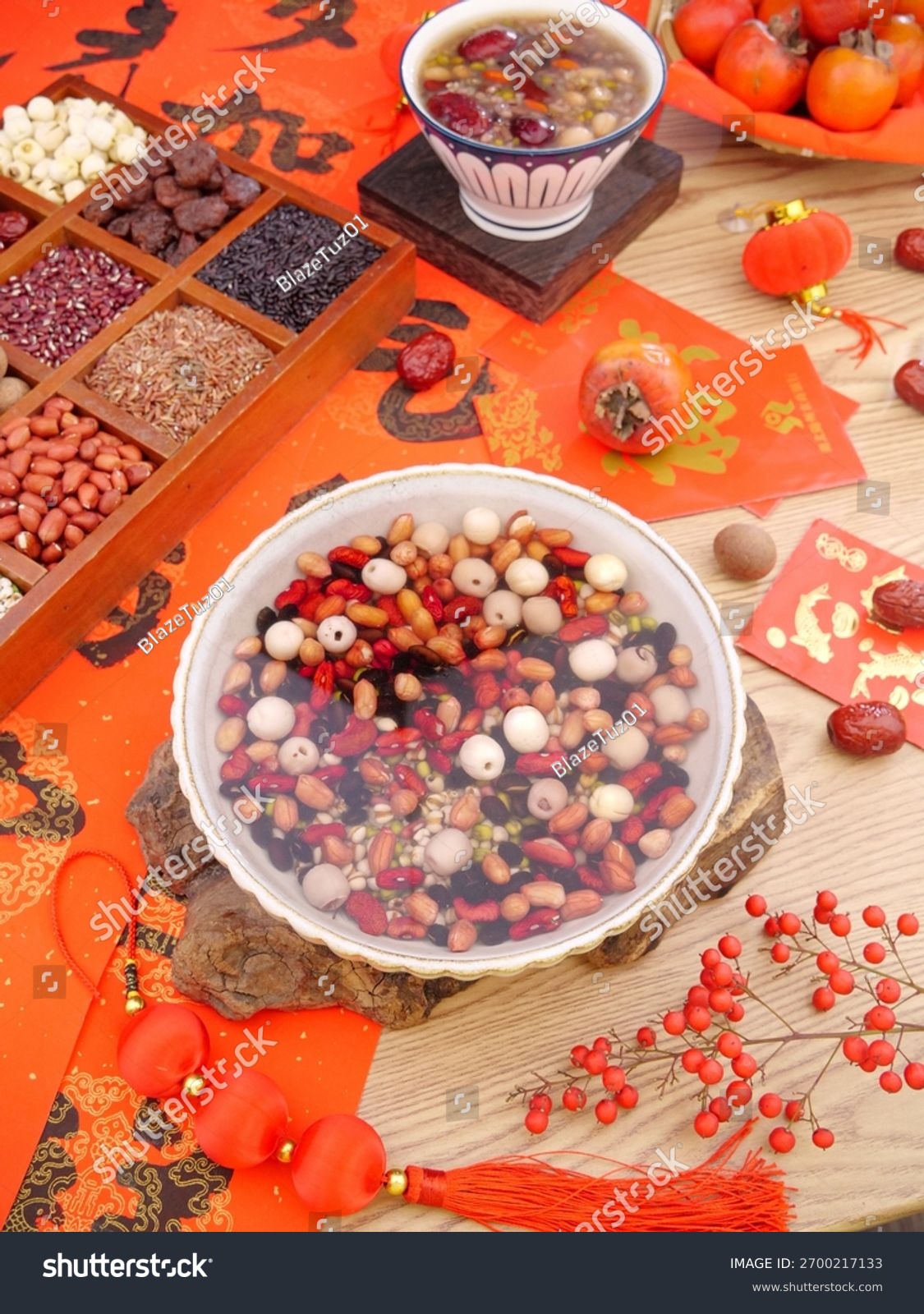 Traditional Chinese Laba congee with mixed beans  nuts and red dates served in bowls with festive red decorations and persimmons for lunar new year celebration