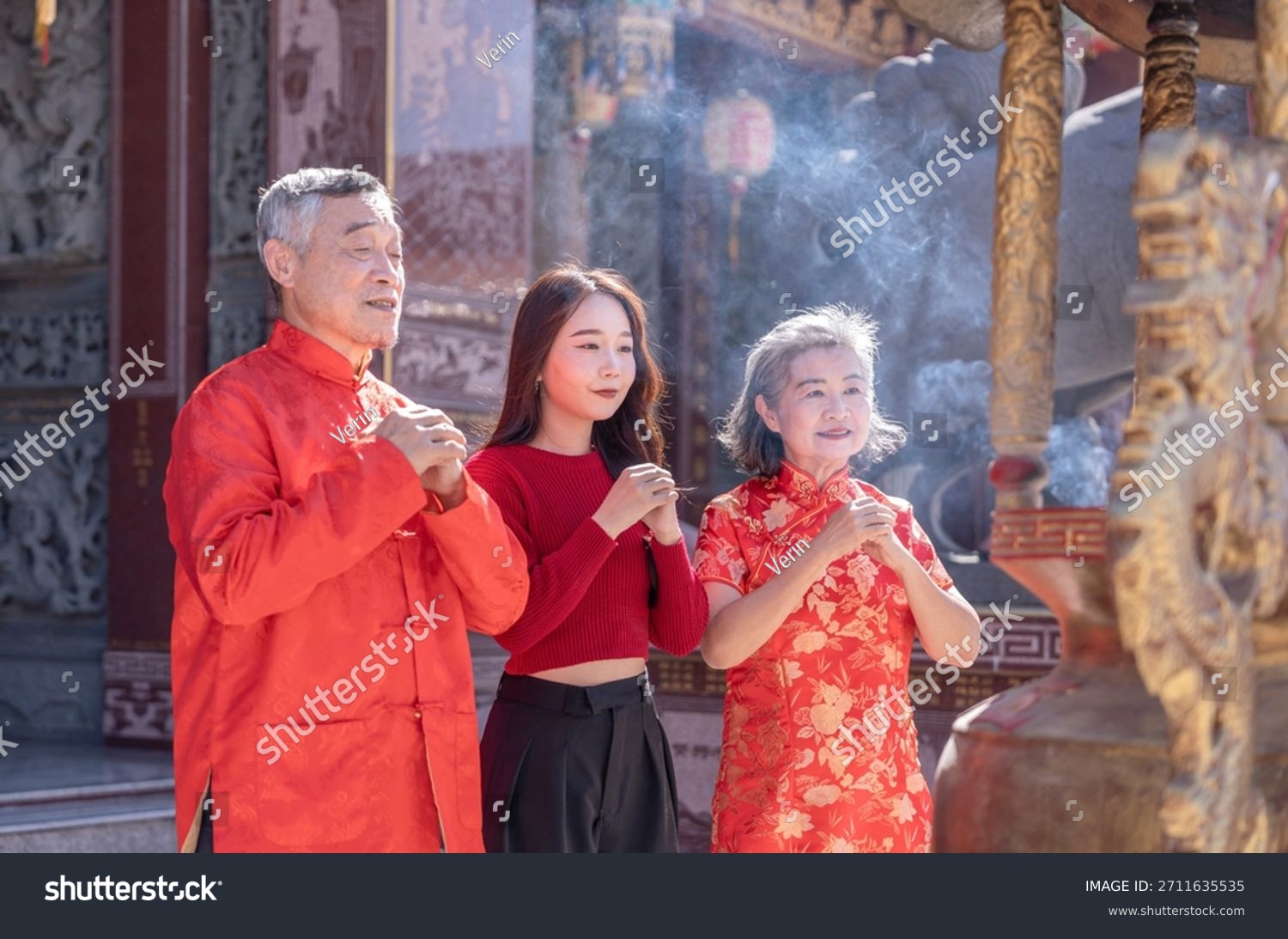 asian family in cheongsam pray and worship together at incense burner in chinese temple chinese new year concept