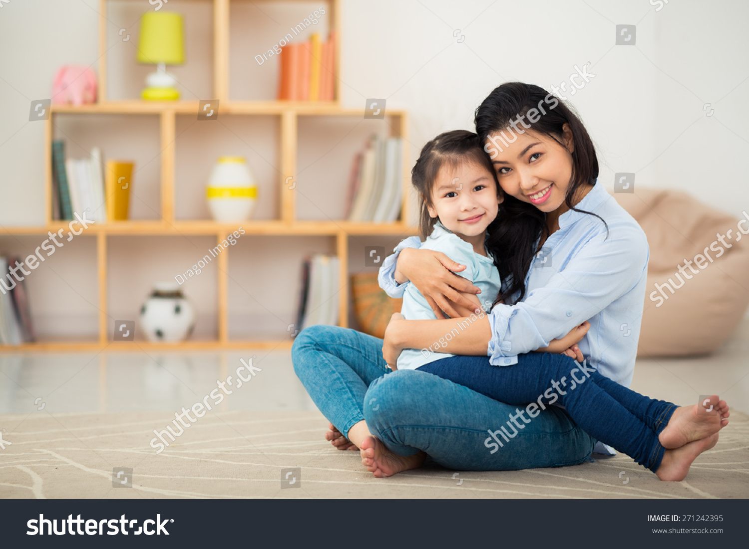 Portrait of happy young woman and her daughter hugging and looking at the camera