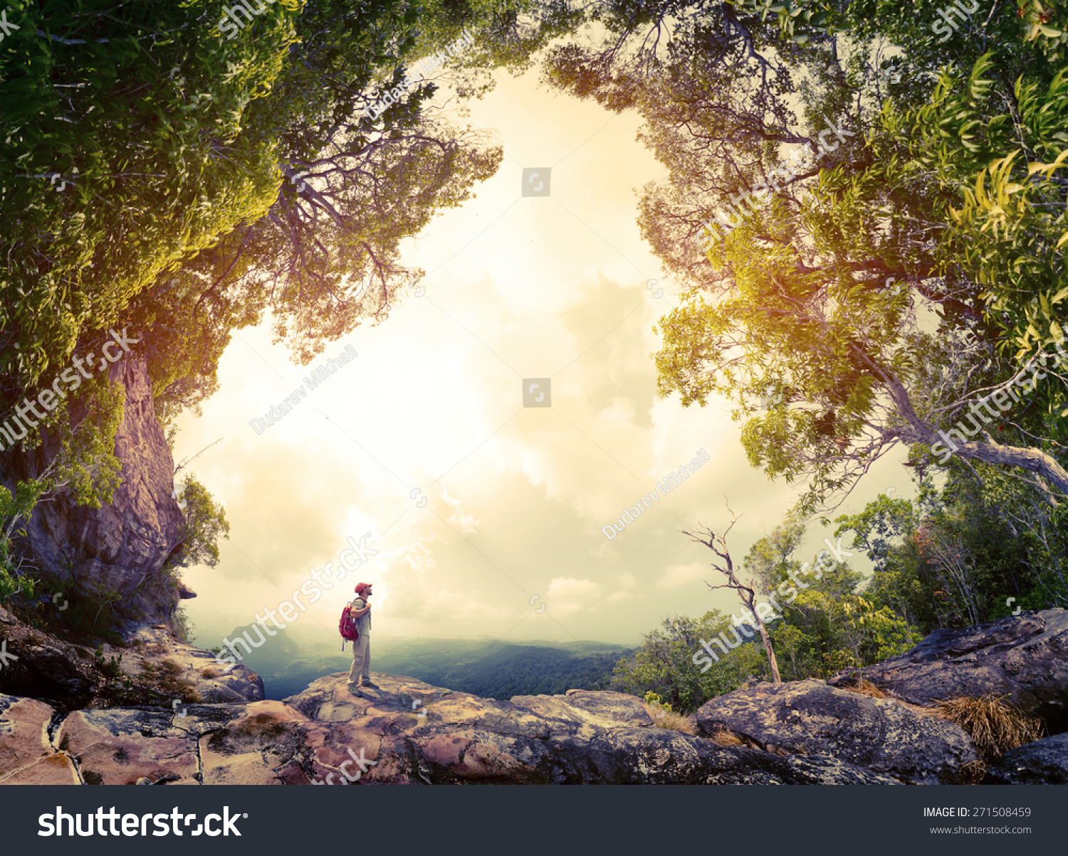 Hiker with backpack standing on the rock surrounded by lush tropical forest