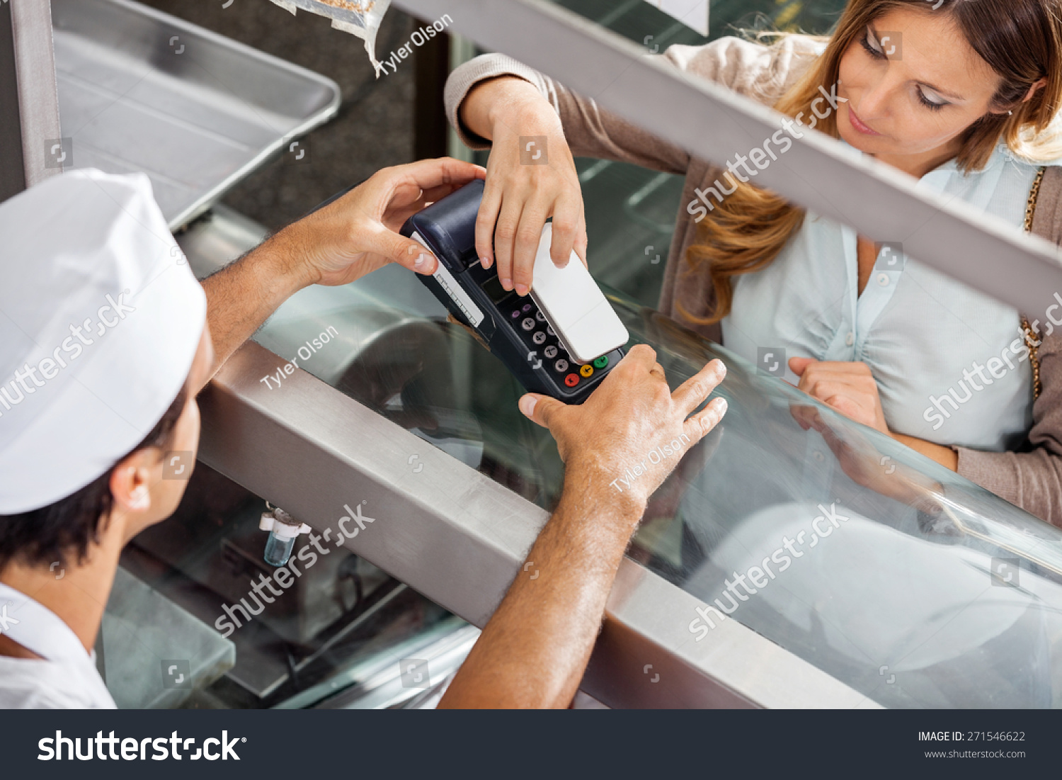 High angle view of mature female customer paying through smartphone at butchery