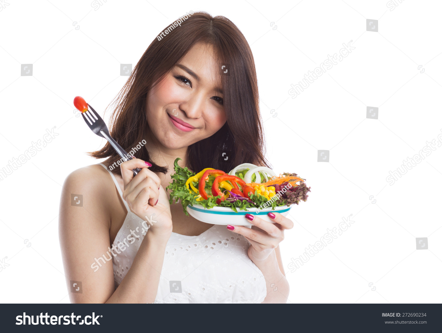 Young woman eating a vegetable salad on white background