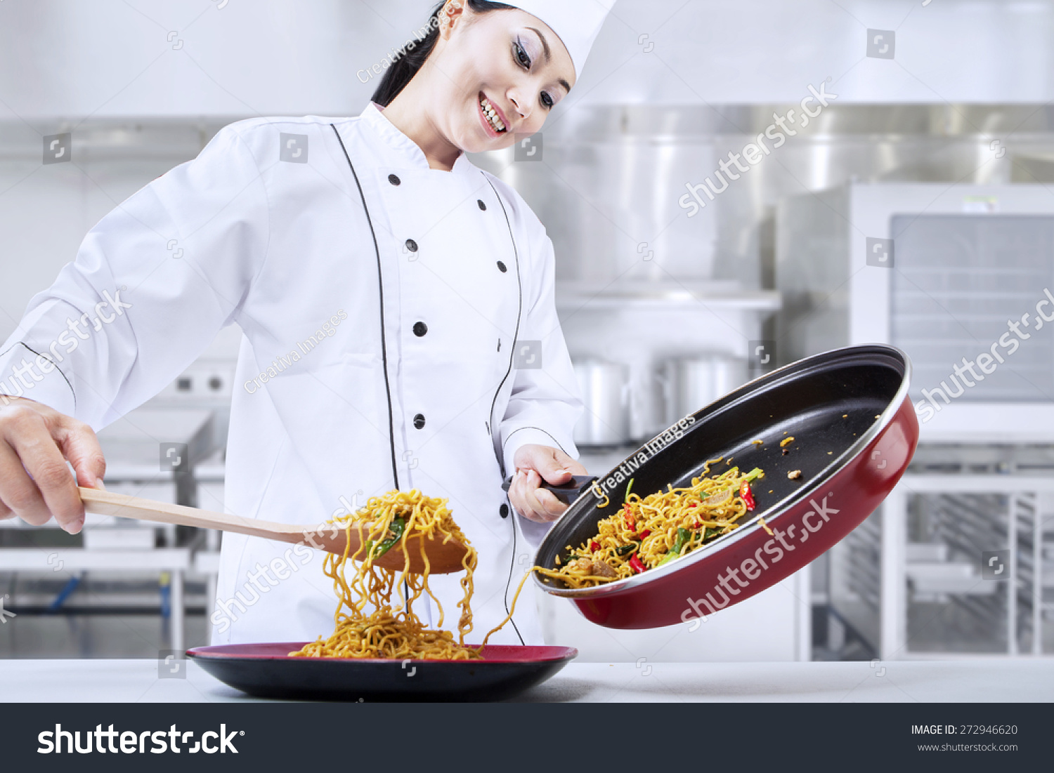 Beautiful asian chef cooks fried noodle in the kitchen