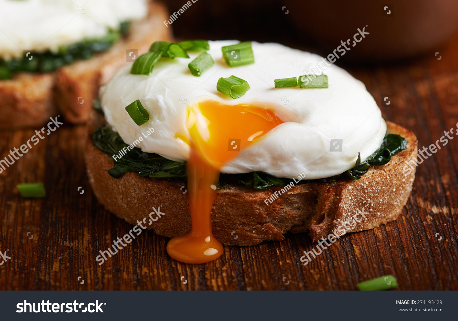 Poached egg on a piece of bread with spinach on the wooden table