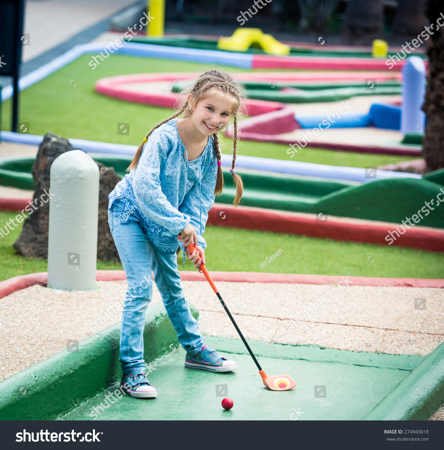 Cute smiling little girl playing golf