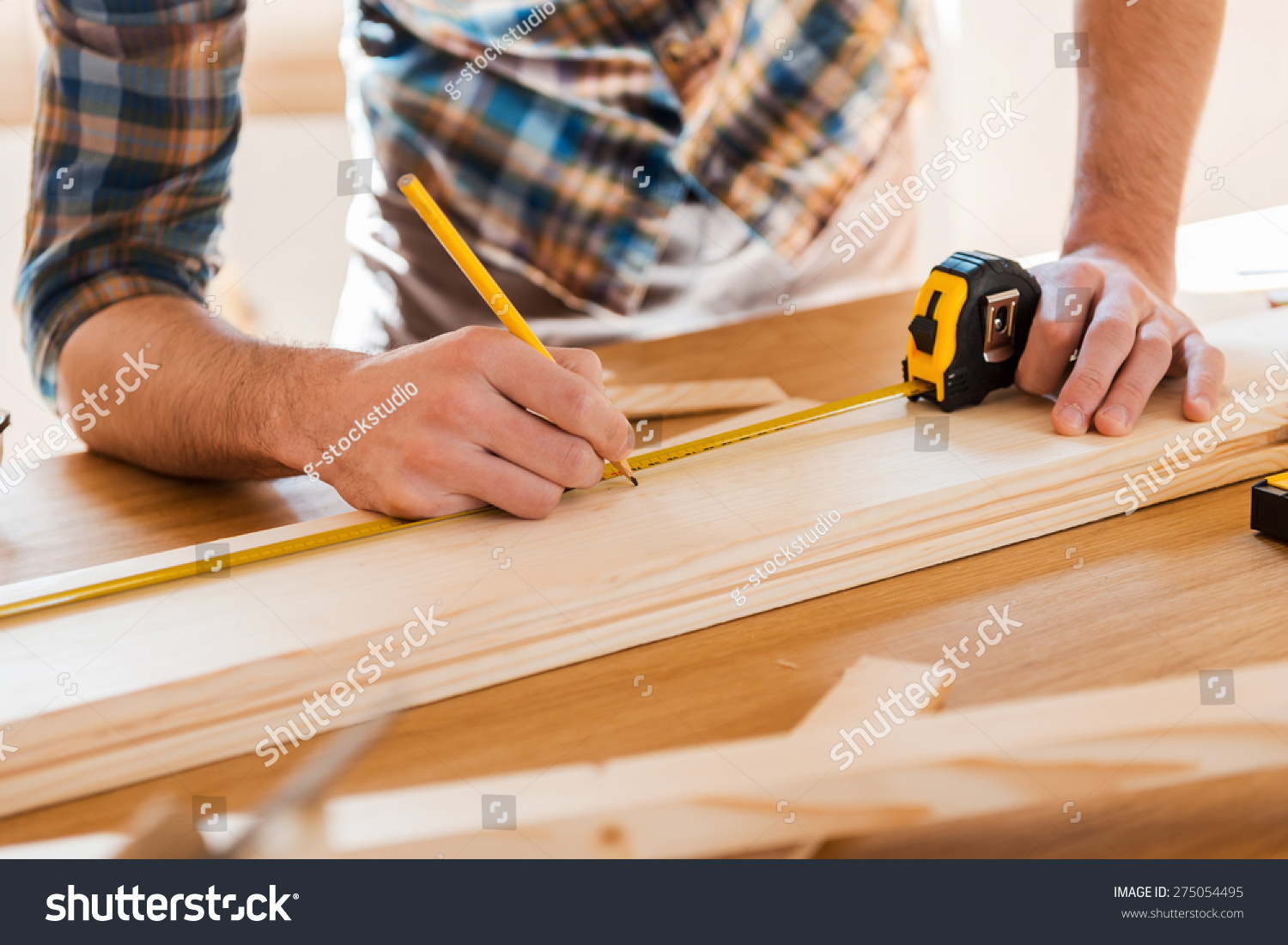 exactmeasuredcloseupofyoungmalecarpentermakingmeasurementsonthe