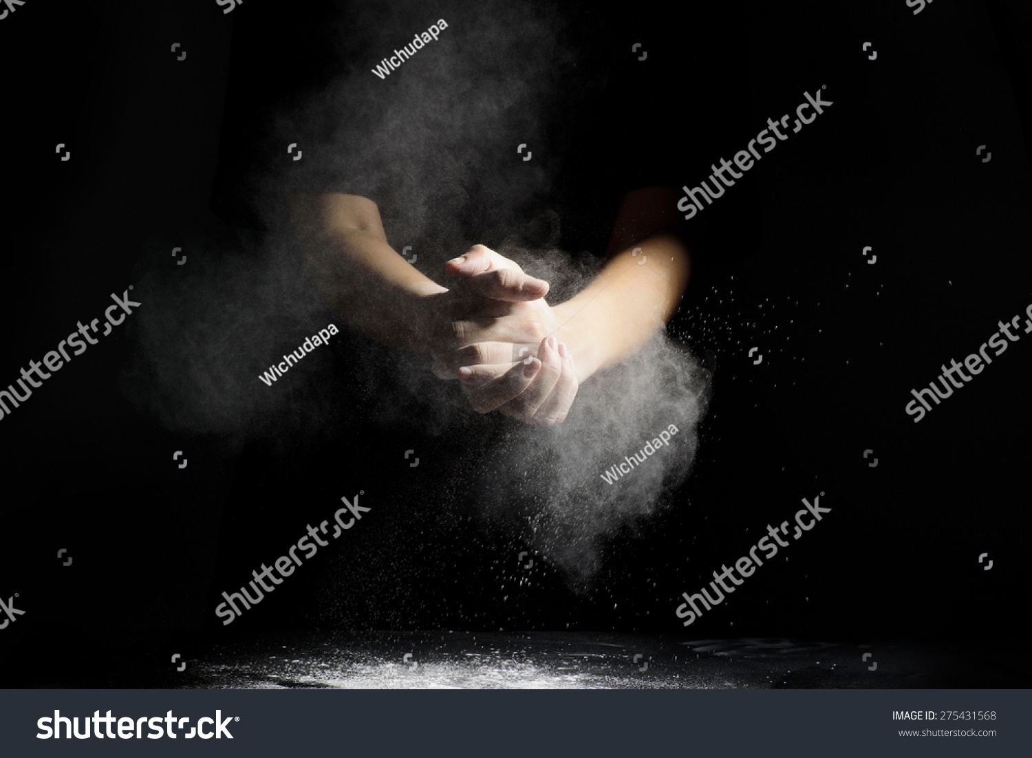 Chef hand clap and white flour on black background