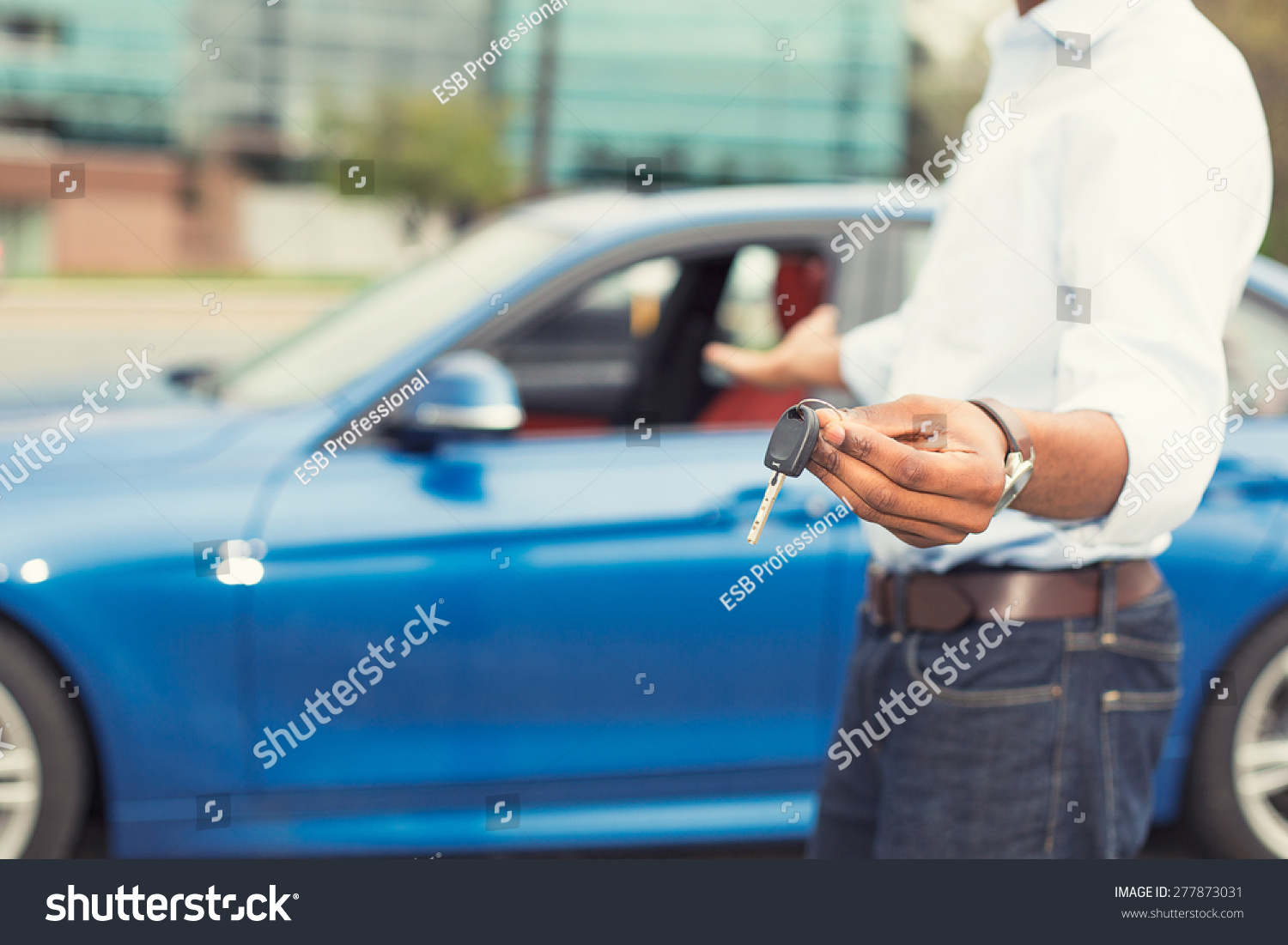 Male hand holding car keys offering new blue car on background