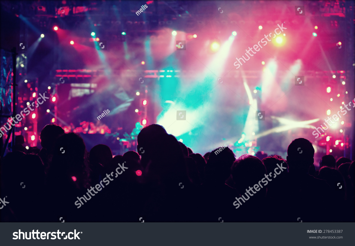 Cheering crowd in front of bright colorful stage lights - retro styled photo 
