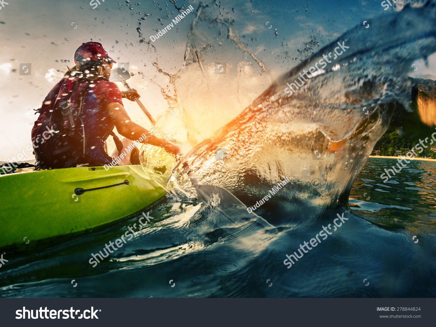 Young lady paddling hard the kayak with lots of splashes