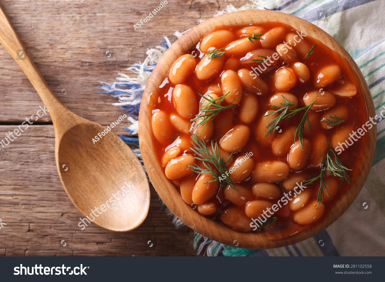 white beans in tomato sauce in a wooden bowl closeup. Horizontal top view