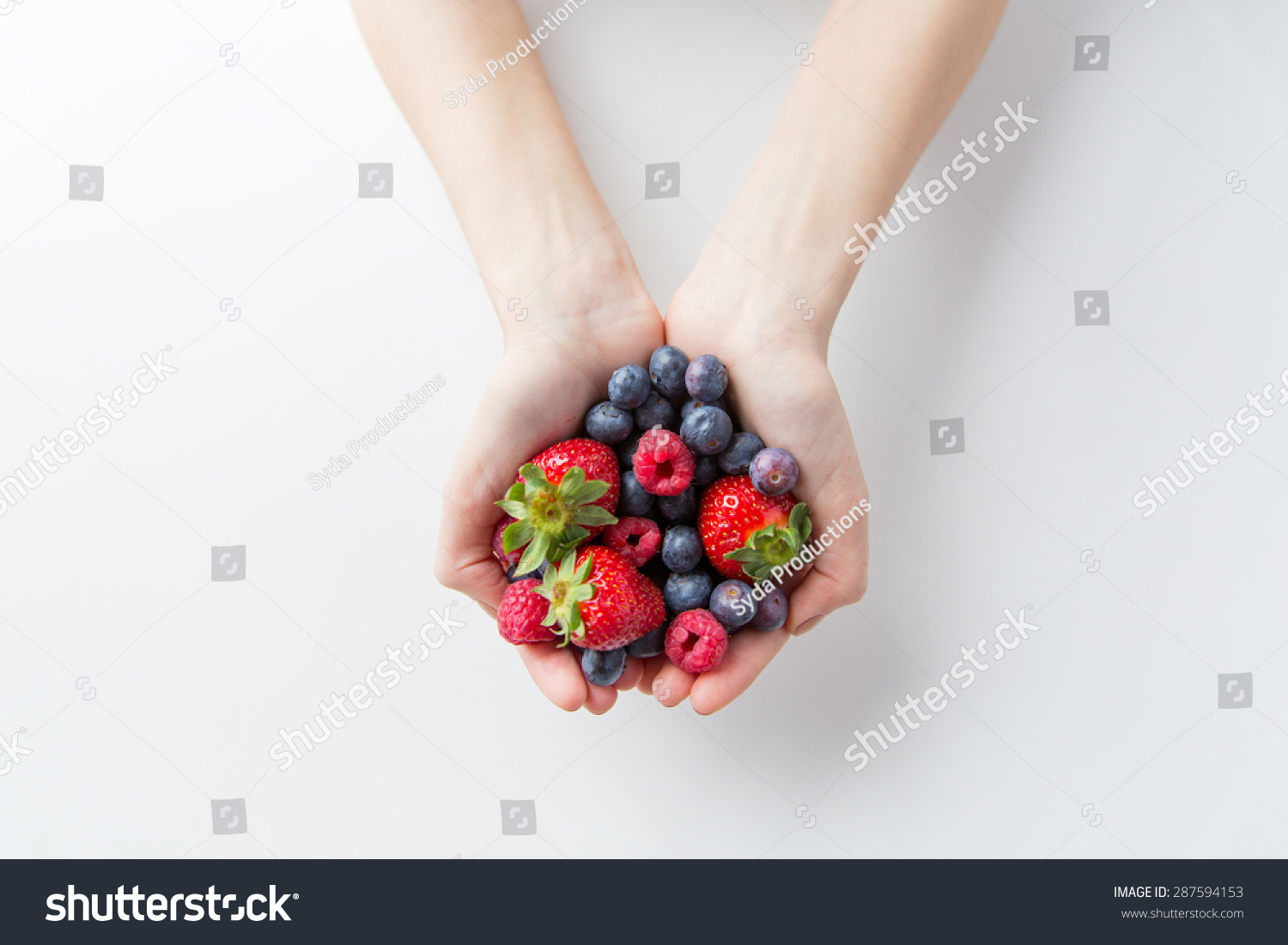 healthy eating dieting vegetarian food and people concept - close up of woman hands holding berries at home