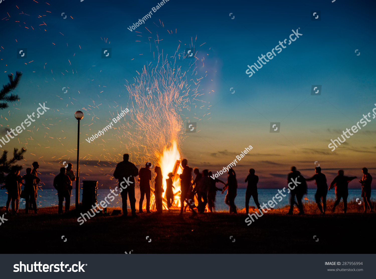 People resting near big bonfire outdoor at night
