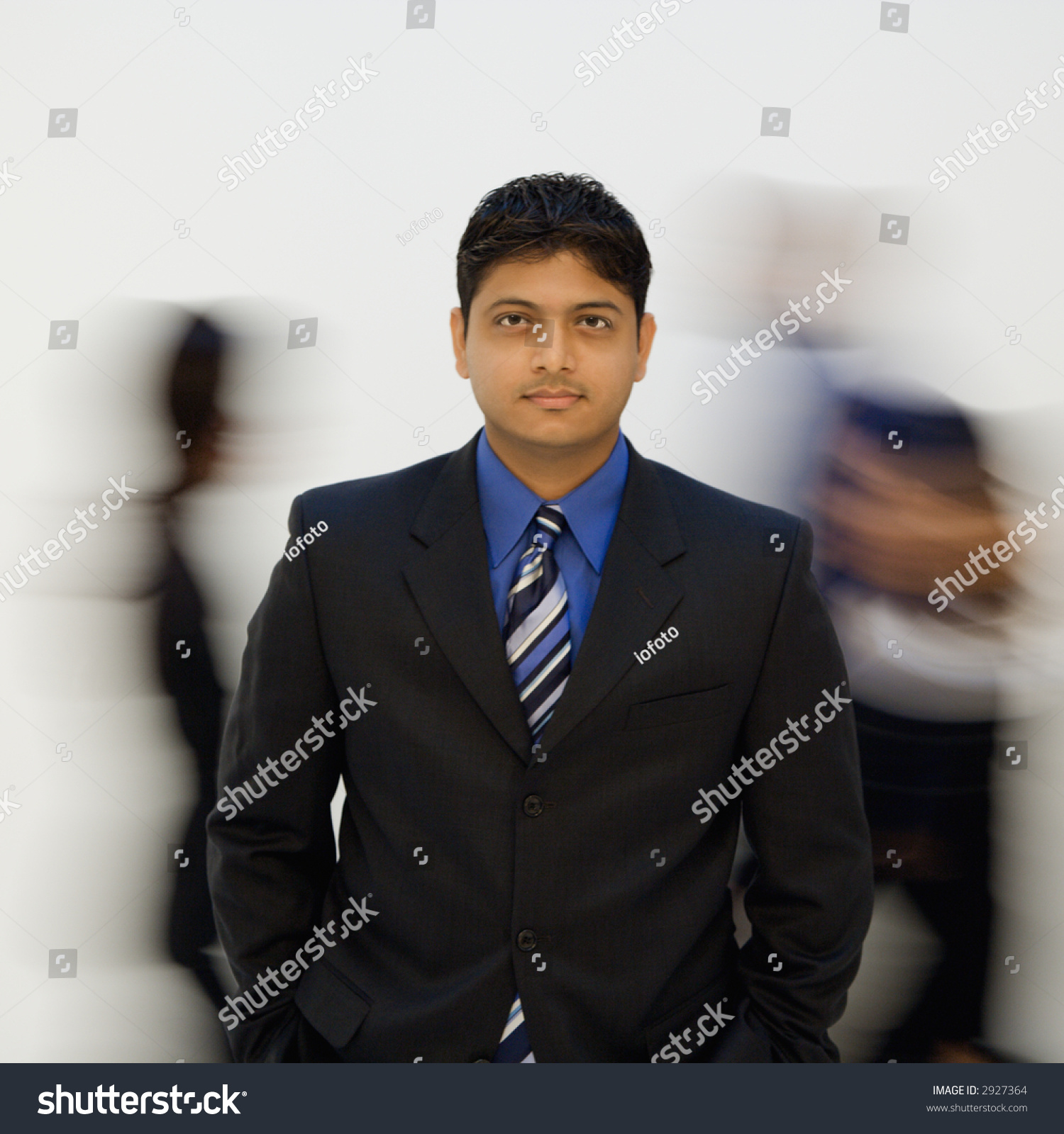 indian businessman standing with hands in pockets while others