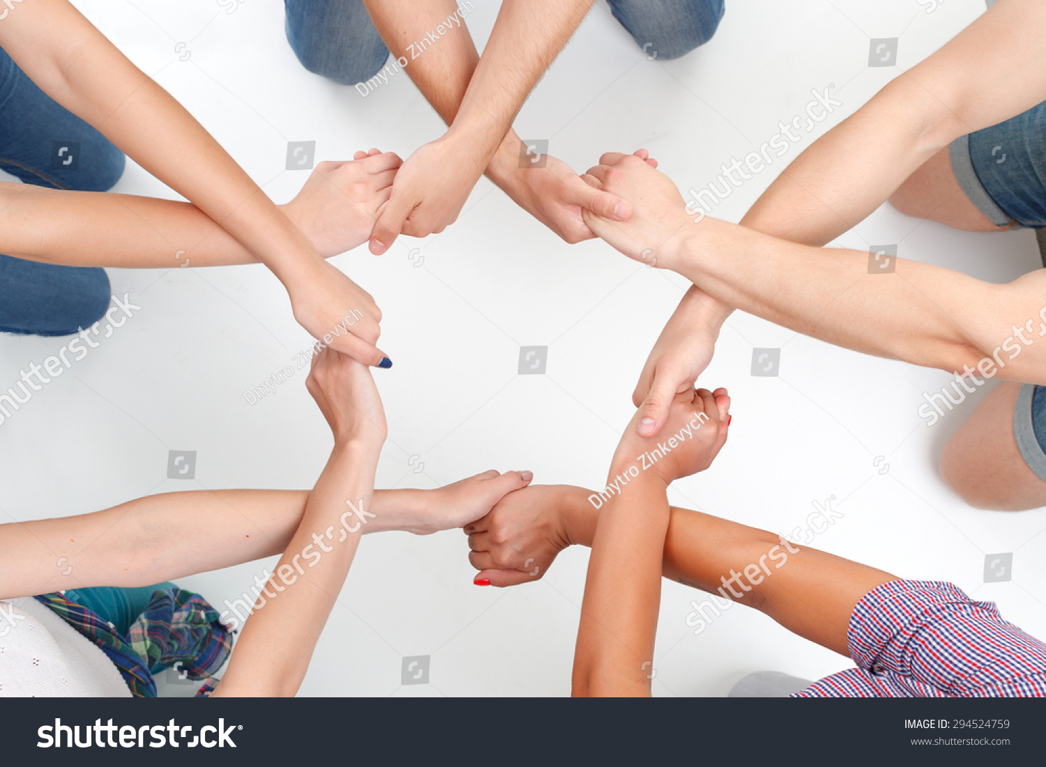 Team work. Group of young friendly people making ring of hands on white isolated background.