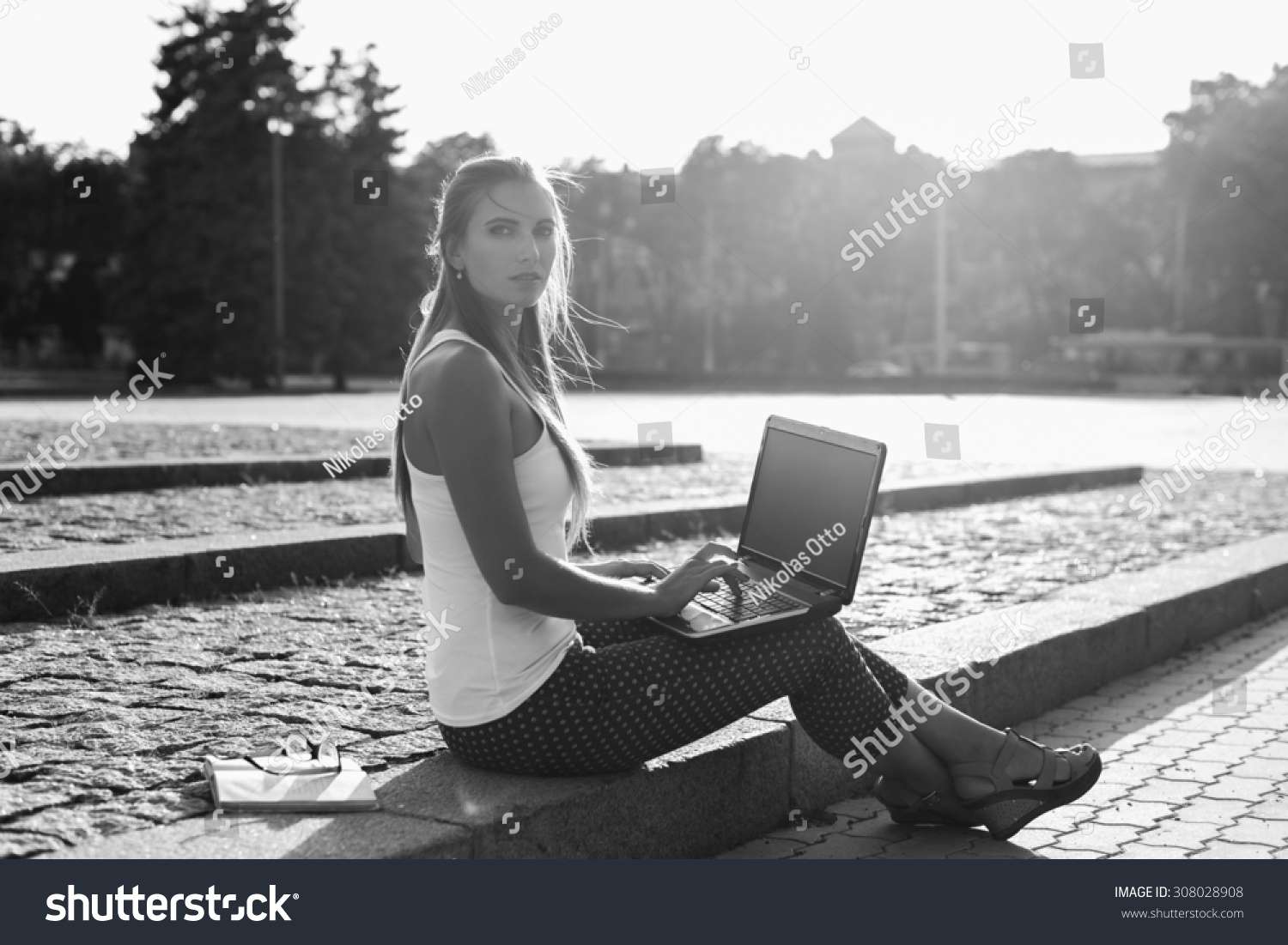 Black and White. BW. Student sitting in park near the grass working on laptop at campus