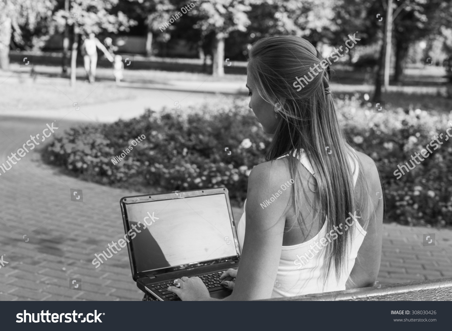 Black and White. BW. Portrait. Student sitting in park near the grass working on laptop at campus
