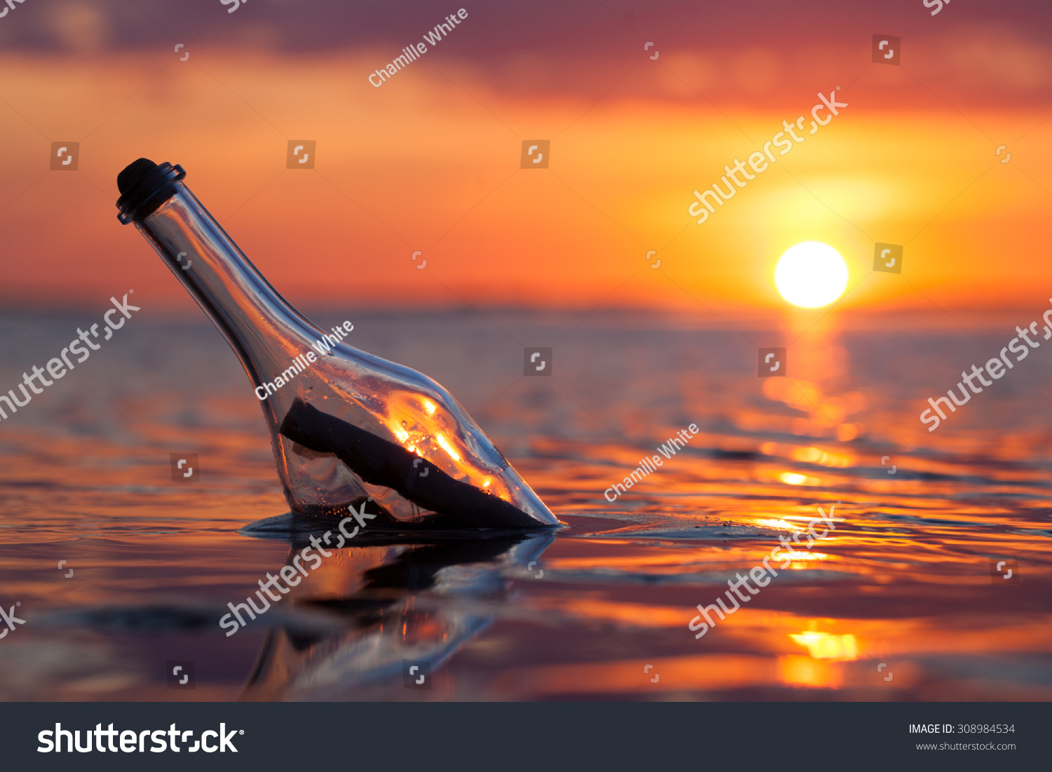 Bottle with a message in the sea at sunset