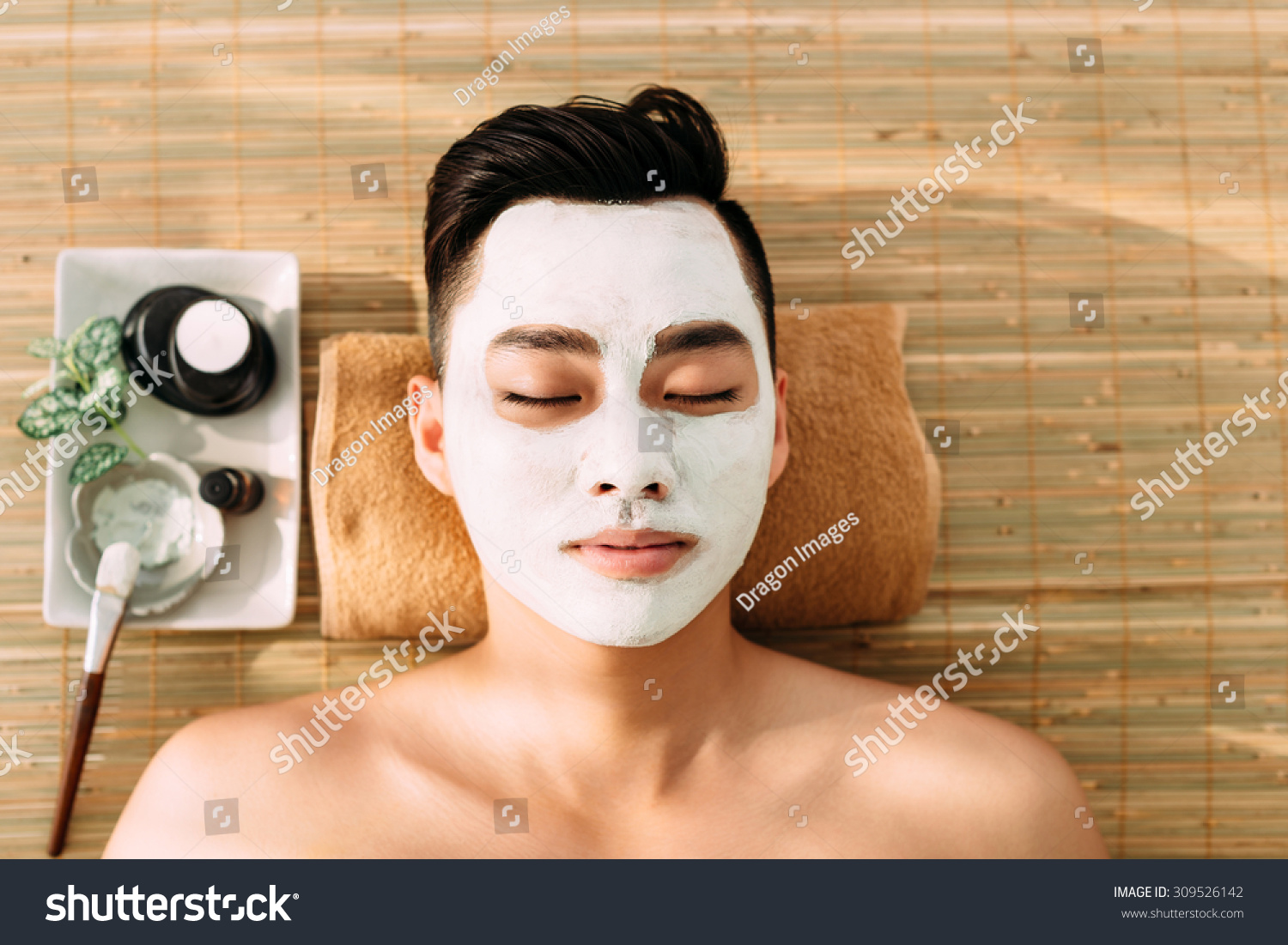 Asian young man in spa salon with facial mask on his face