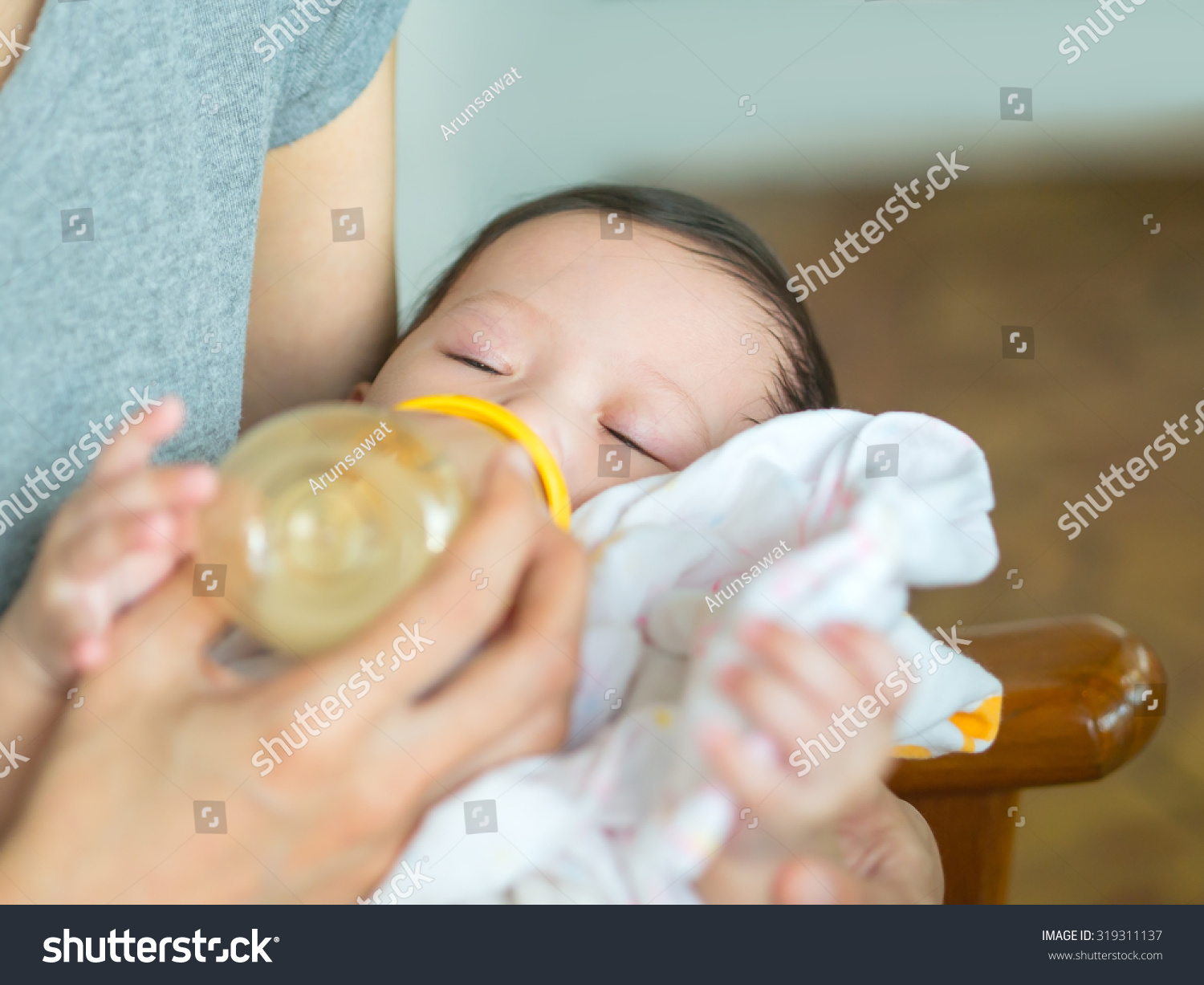 Asian mother feeding bottle her baby while baby sleeping.