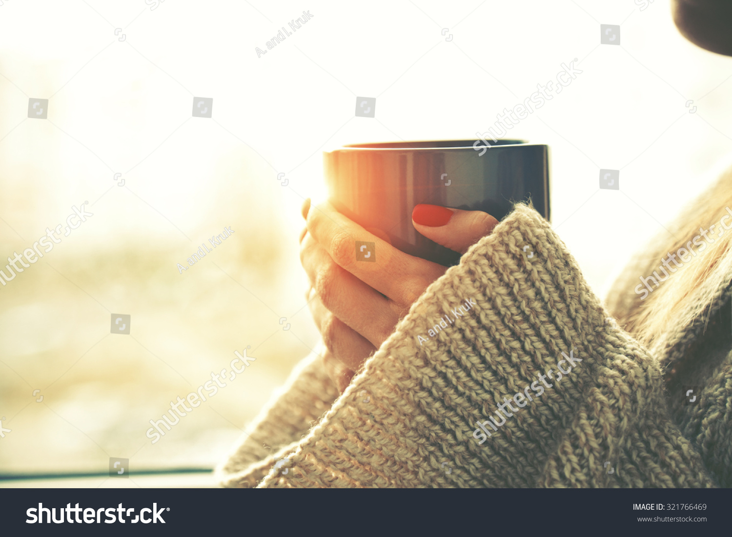 hands holding hot cup of coffee or tea in morning sunlight