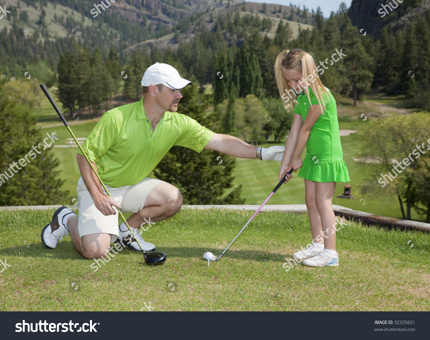 Full length view of father and giving young daughter golf lesson.