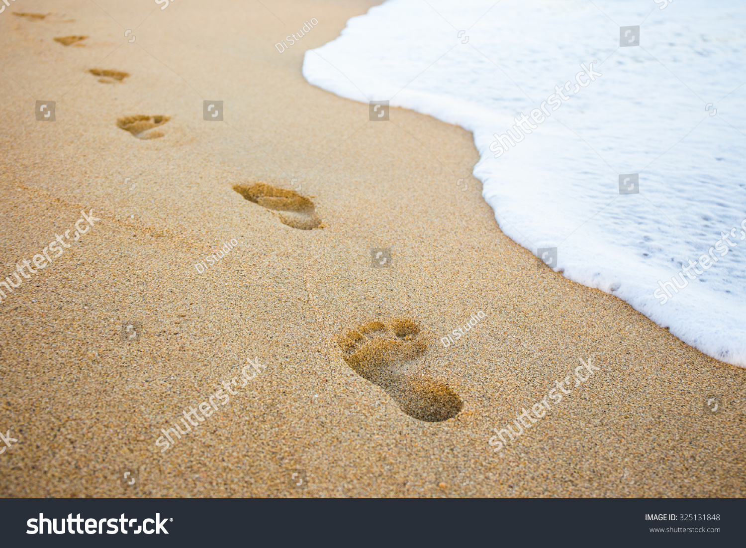 close up of footprints in the sand and sea wave