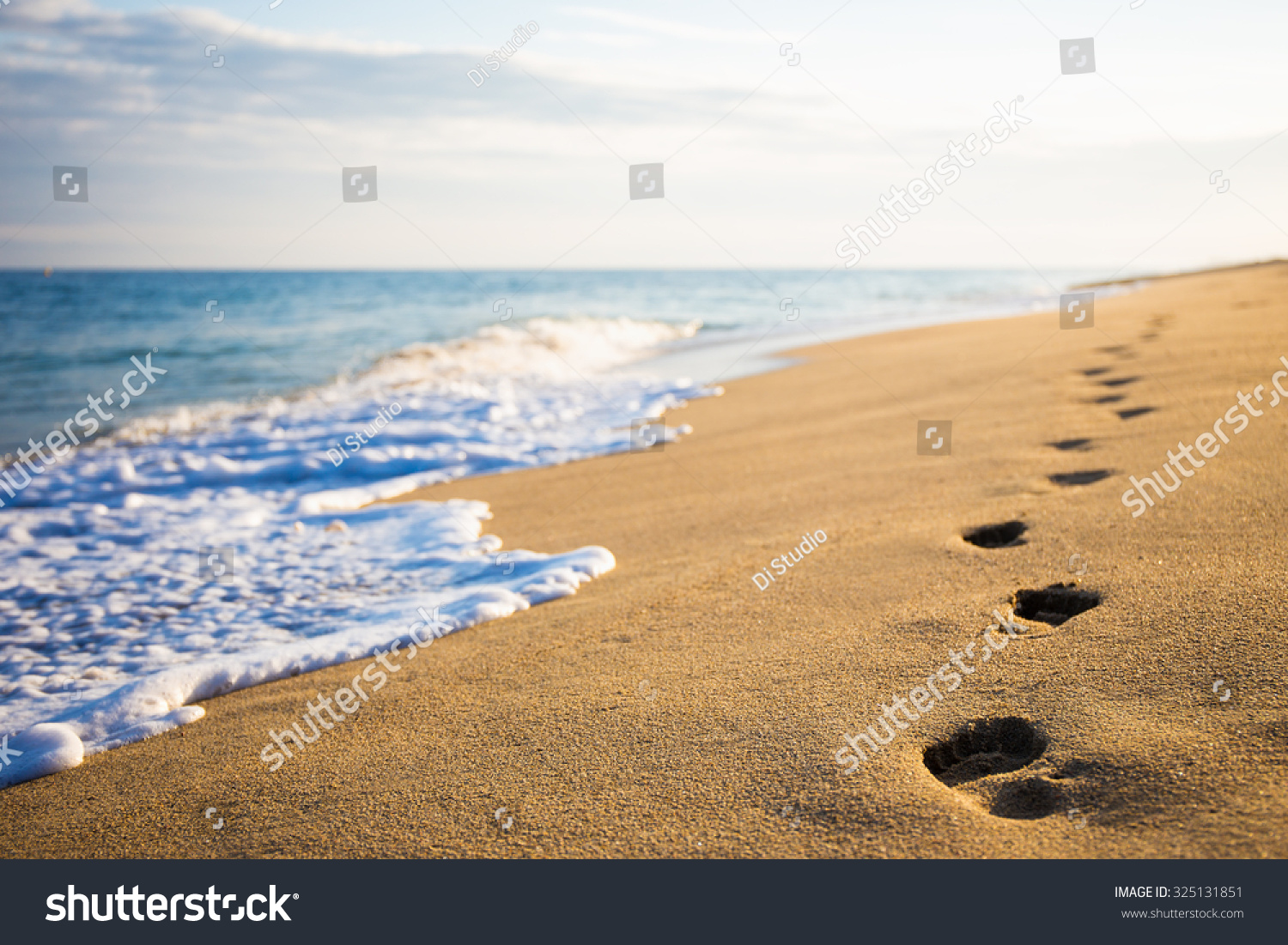 close up of footprints on the beach with golden sand