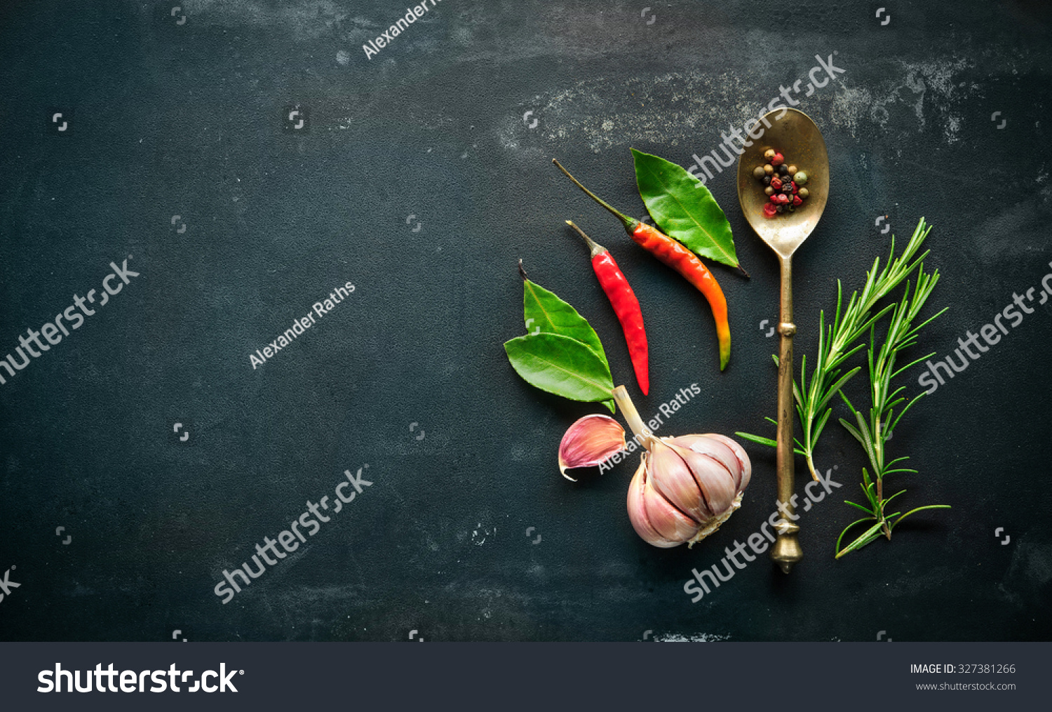 Herbs and spices with old metal spoon on slate background