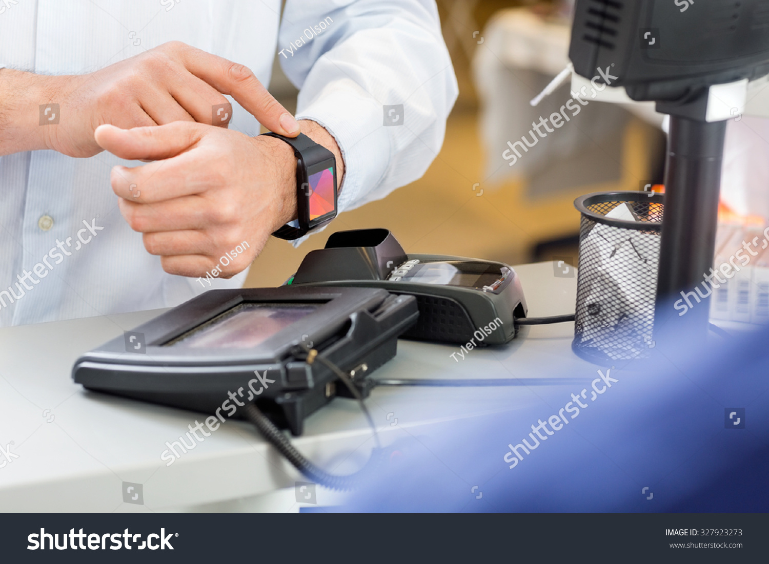 Closeup of male customer paying through smartwatch at counter in pharmacy