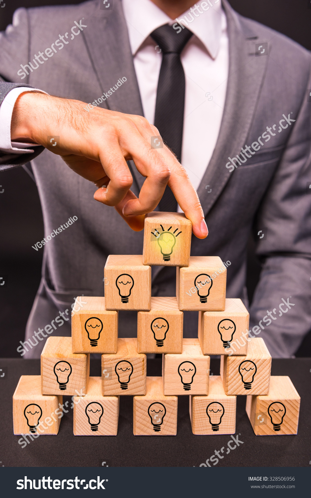 Creative idea. Young businessman presenting creative idea using wood cubes. Studio shooting isolated on Black background