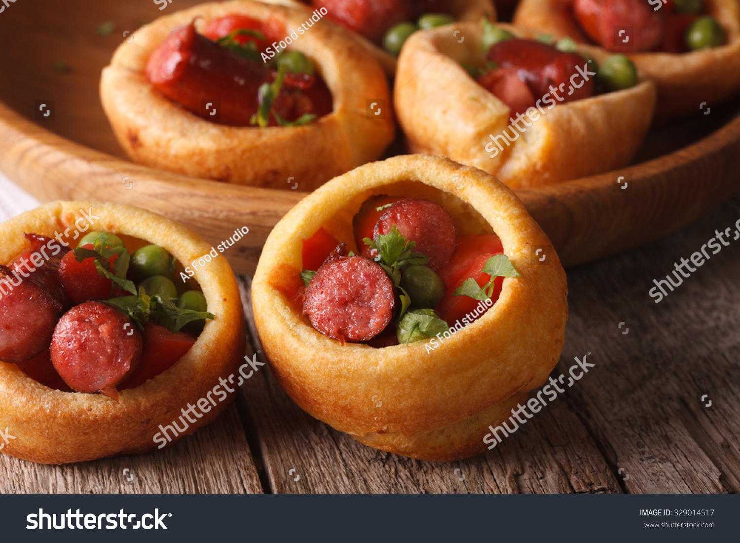 Yorkshire puddings stuffed with sausages and vegetables macro on the table. Horizontal