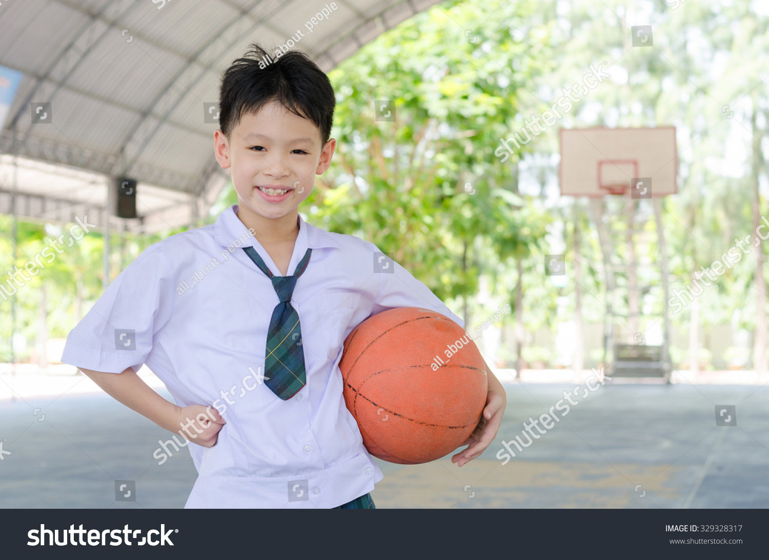 Little Asian student holding basketball at school