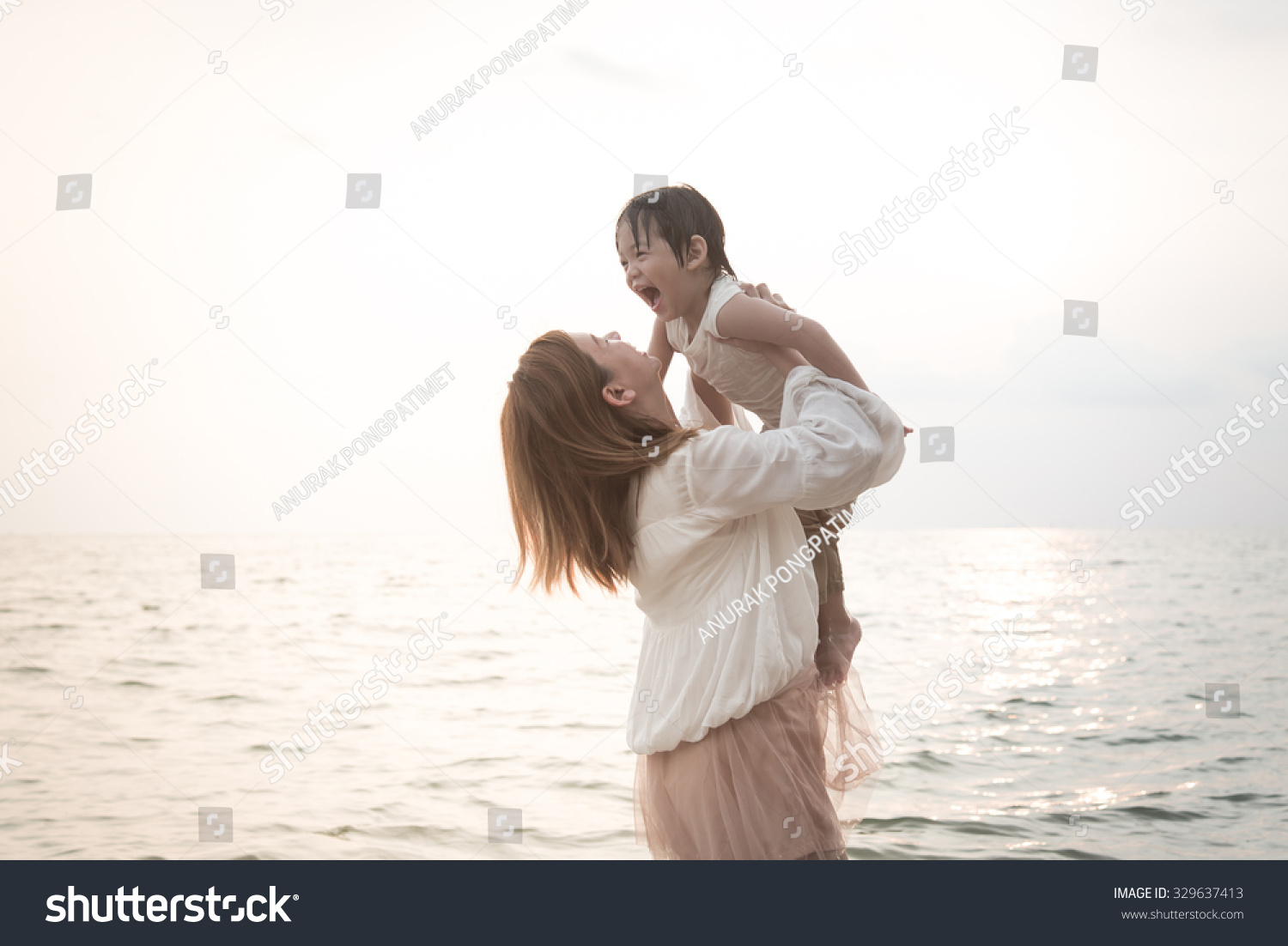 Asian mother and son playing on the beach vintage filter