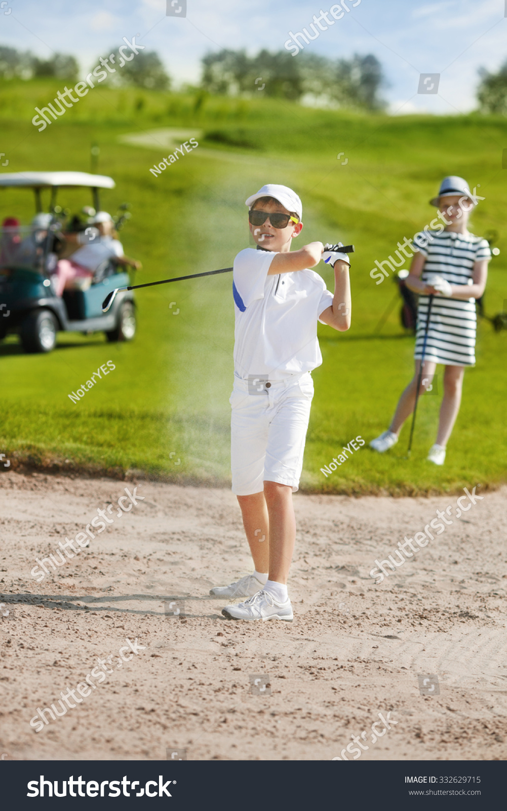Boy playing golf and hitting from bunker 