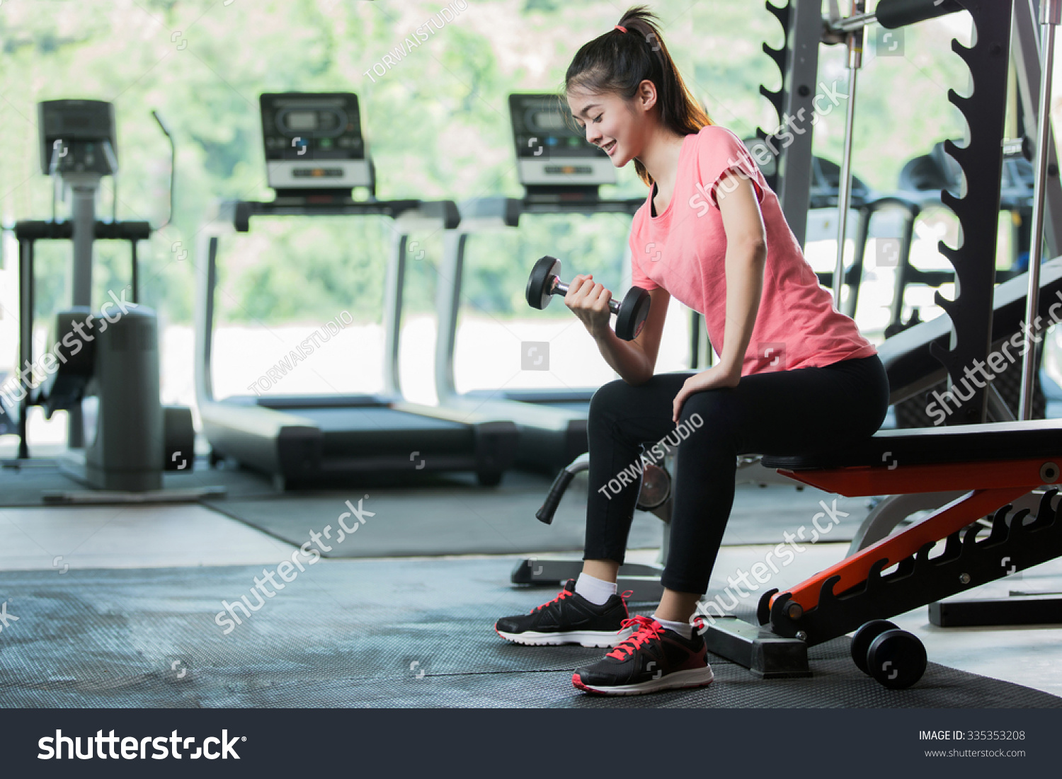 Asian women workout lifting a dumbbell in the gym.
