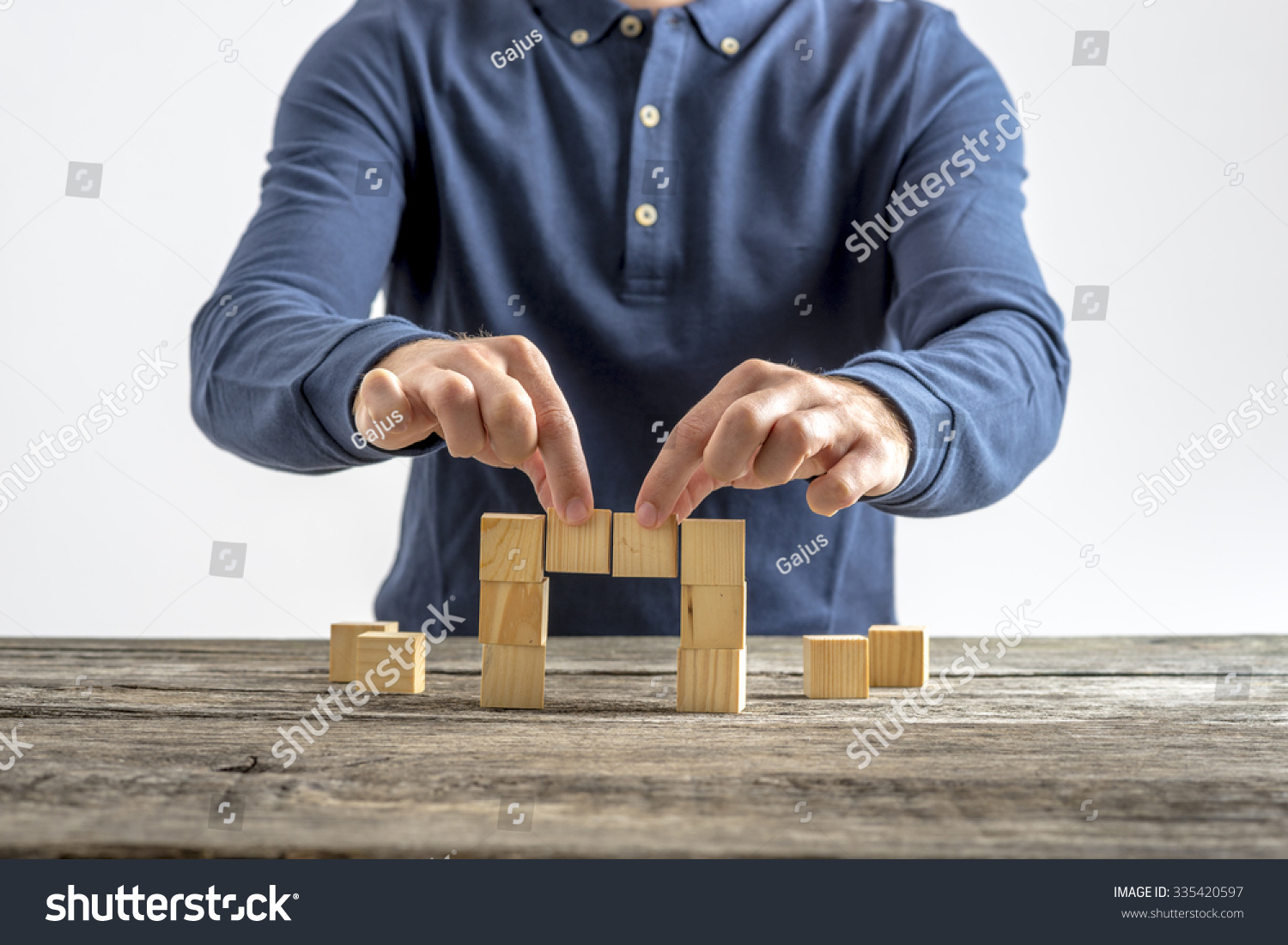 Front view of a man making a bridge with wooden cubes. Conceptual of business  education and construction.