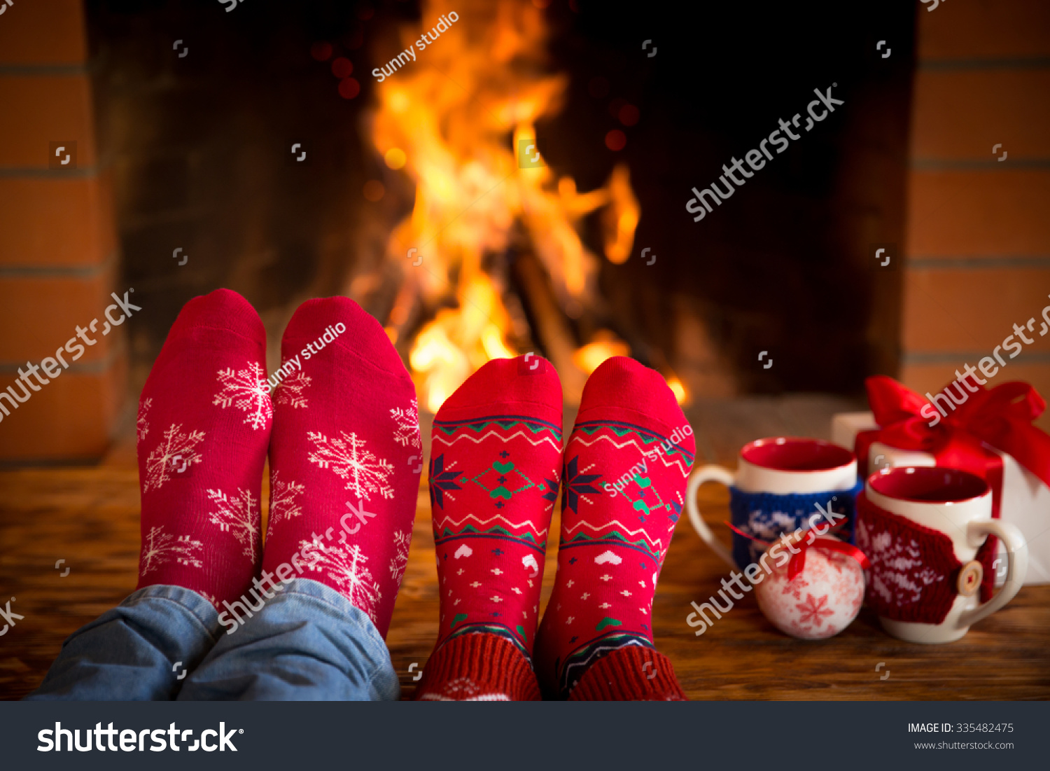 Couple relaxing at home. Feet in Christmas socks near fireplace. Winter holiday concept