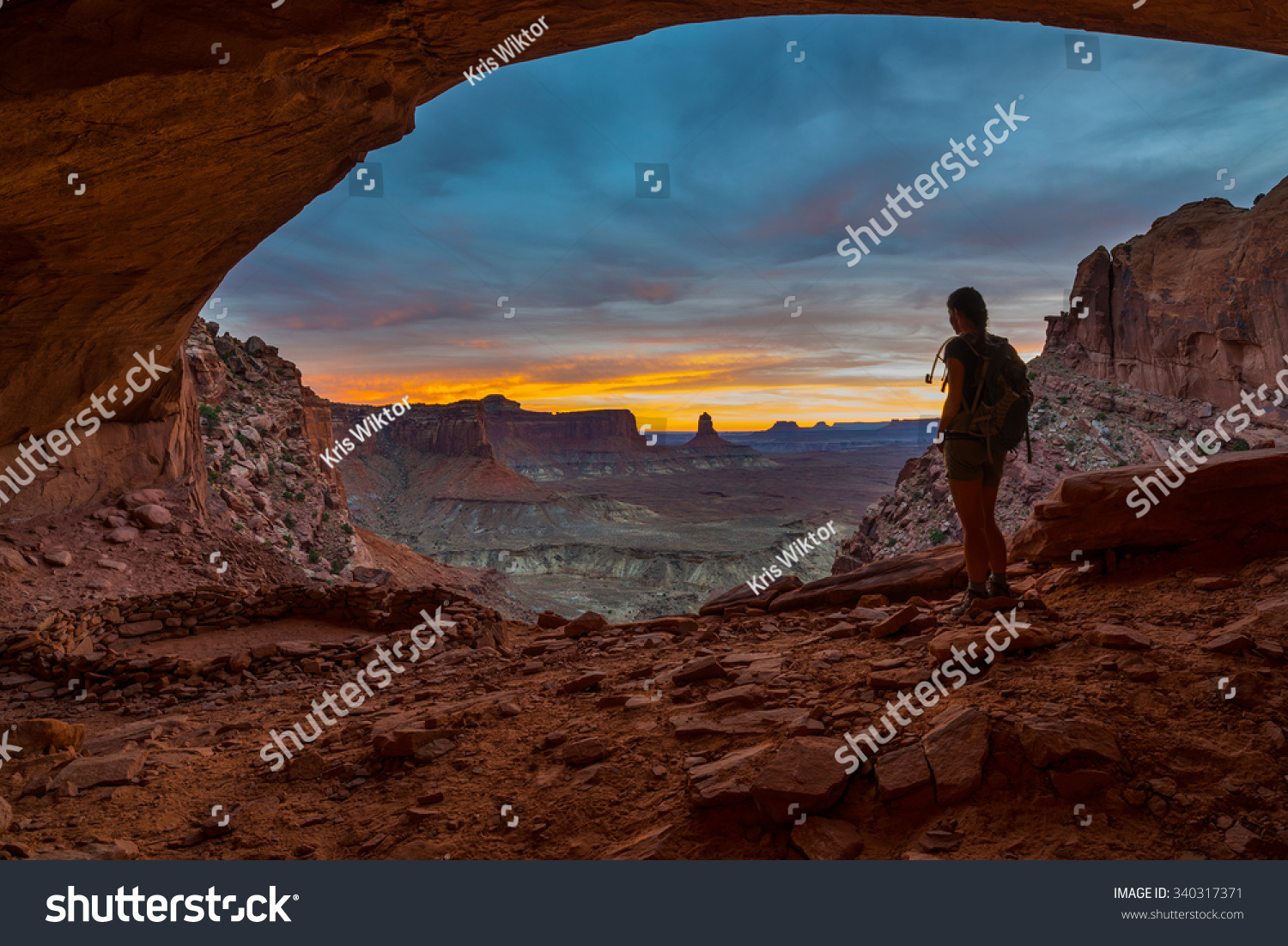 Girl Backpacker looking at beautiful sunset from inside of the False Kiva Canyonlands National Park Moab Utah USA