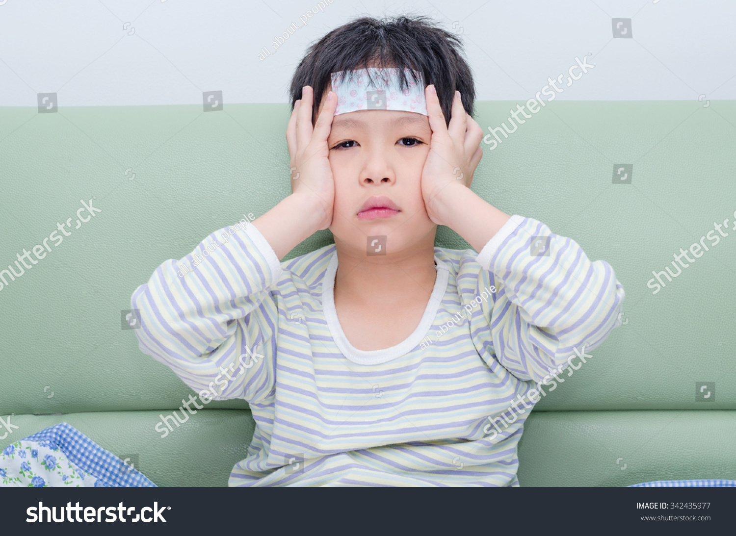 Little sick boy sitting on sofa
