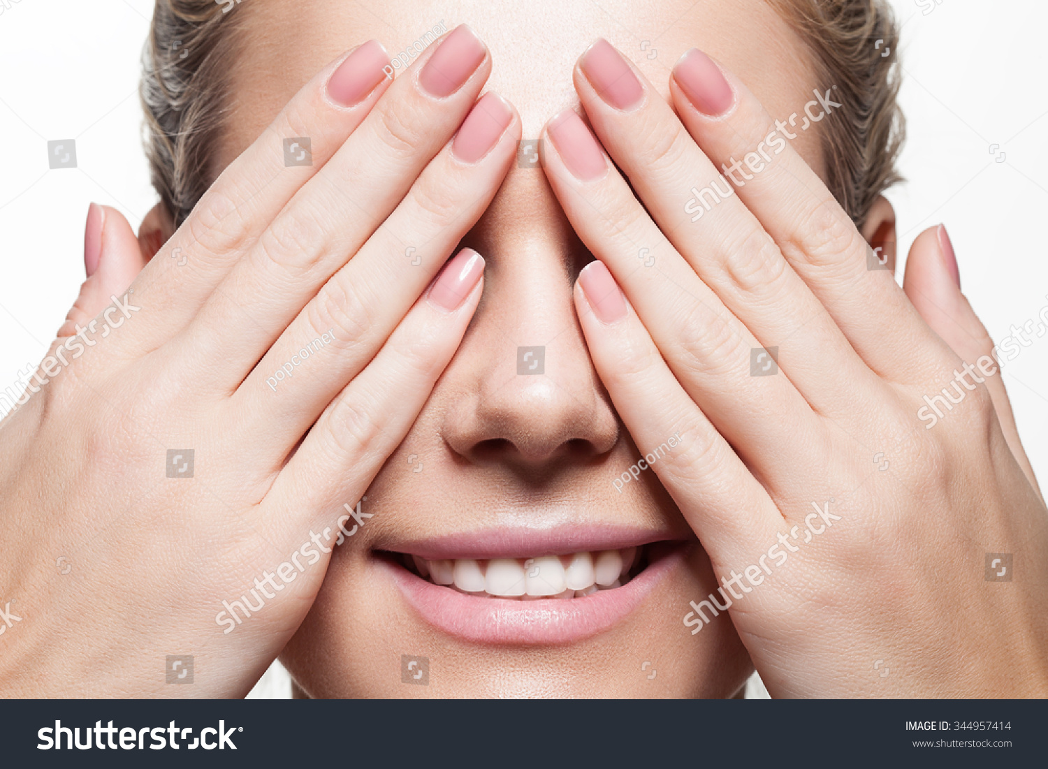Woman with beautiful natural manicure closes eyes with her hands