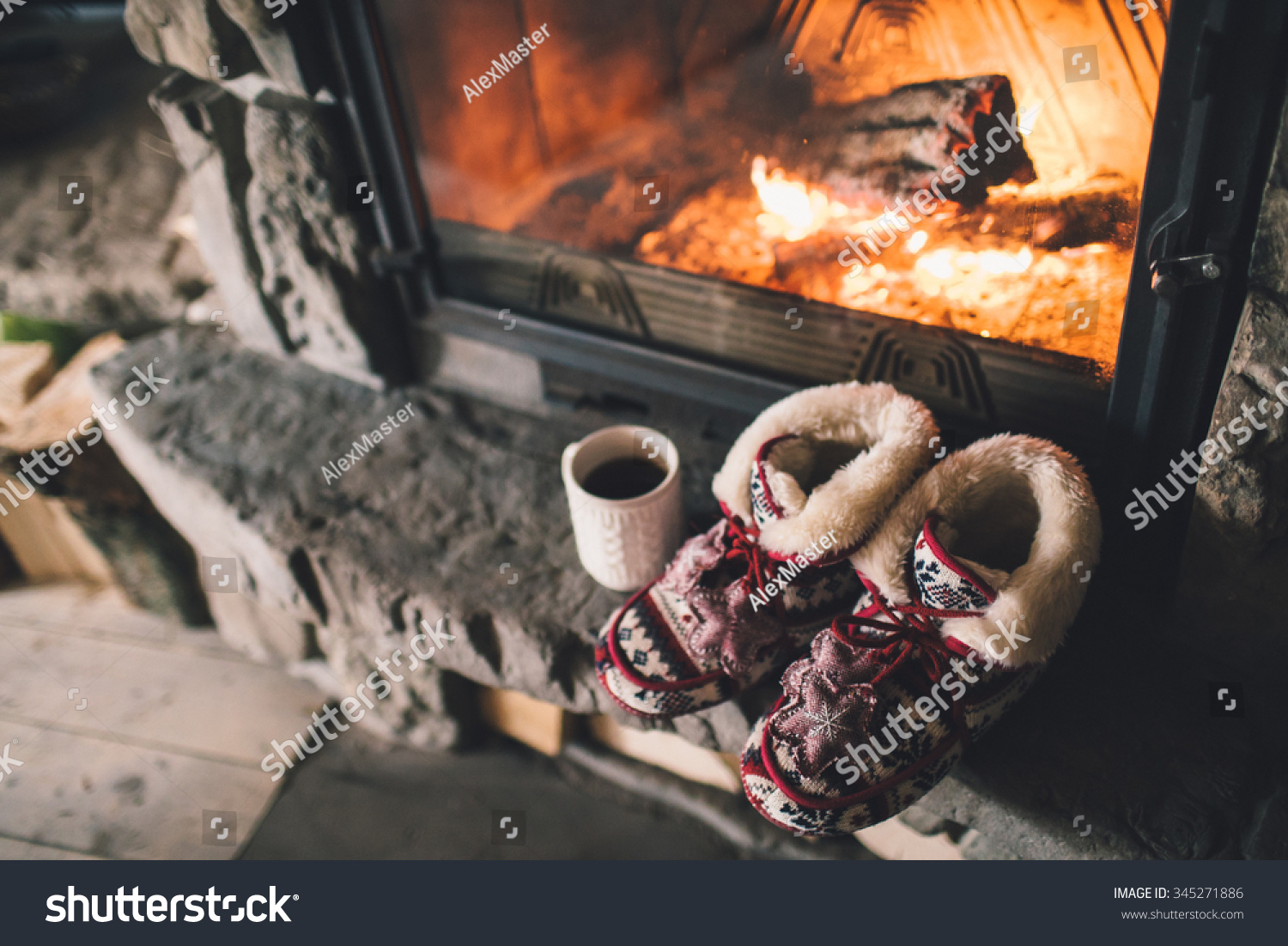 Christmas comfortable slippers by the warm cozy fireplace. Relaxing atmosphere in a chalet by authentic vintage fireside with a cup of hot drink. Winter and Christmas holidays concept.