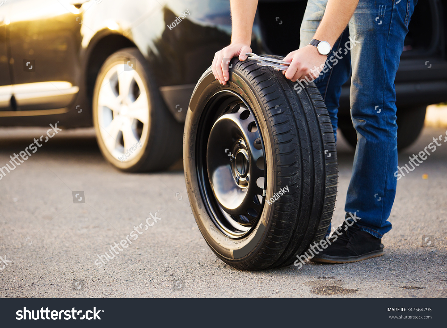 Sad and depressed man sitting near car with punctured tire